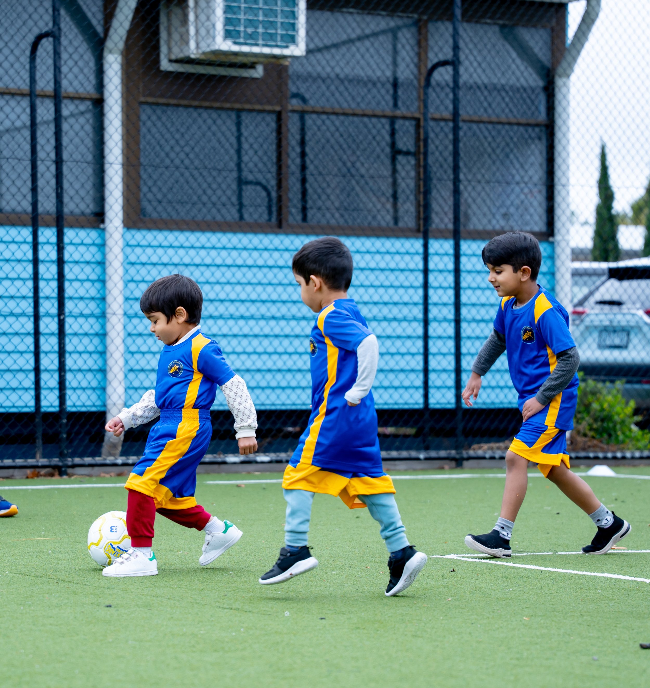 Young boys in blue and yellow soccer uniforms playing soccer on a green artificial turf field