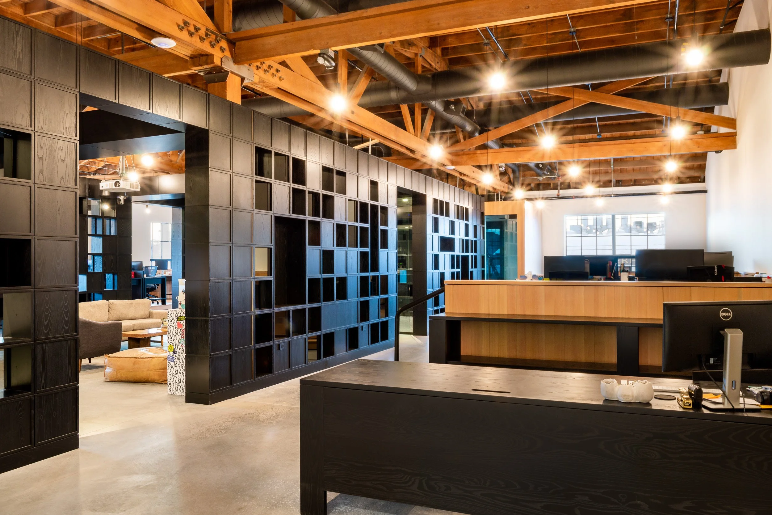 Modern Portland office featuring a custom wood wall divider, intricate panels, and soft warm lighting designed for comfortable working conditions.