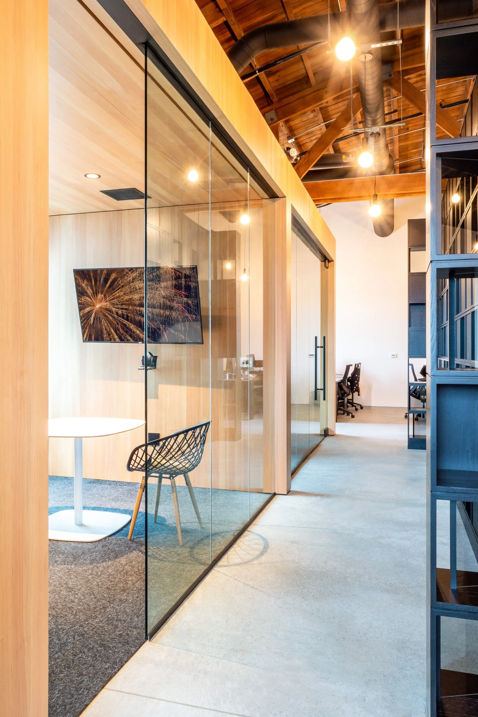 Modern office space in Portland with glass walls, sliding glass doors, wood ceiling beams, and professional electrical work.