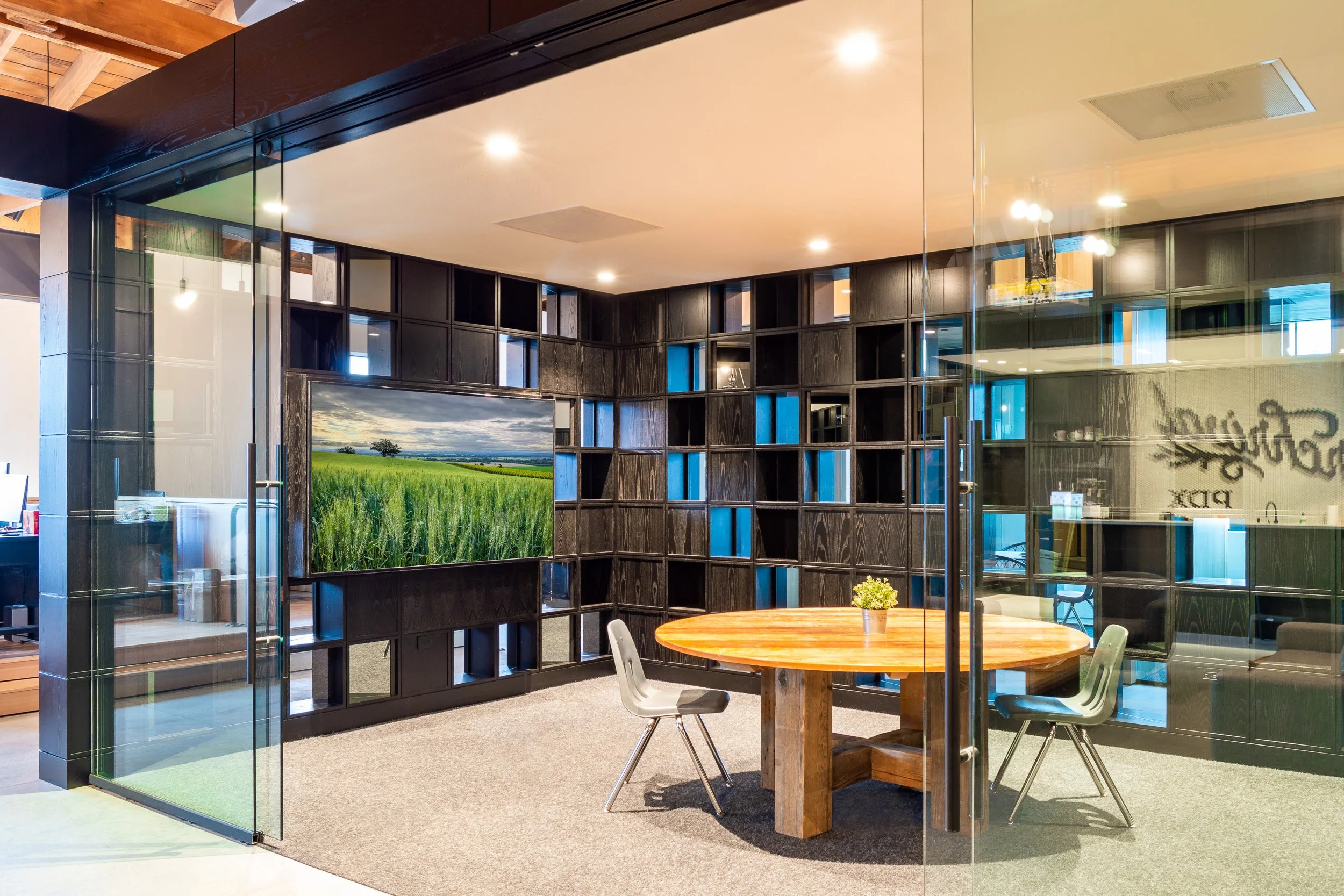 Modern Portland office meeting space with glass walls, sliding doors, recessed lighting, wood beams, soft carpet, and electrical work.