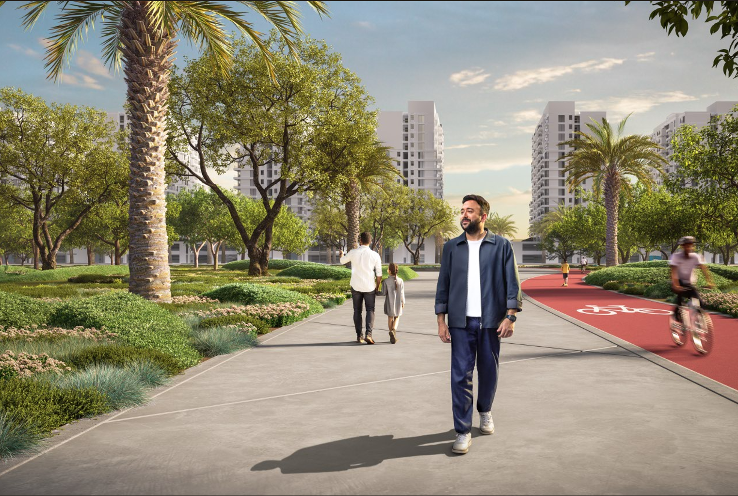 People walking and biking in a modern urban park with trees, landscaping, and tall buildings in the background under a partly cloudy sky.