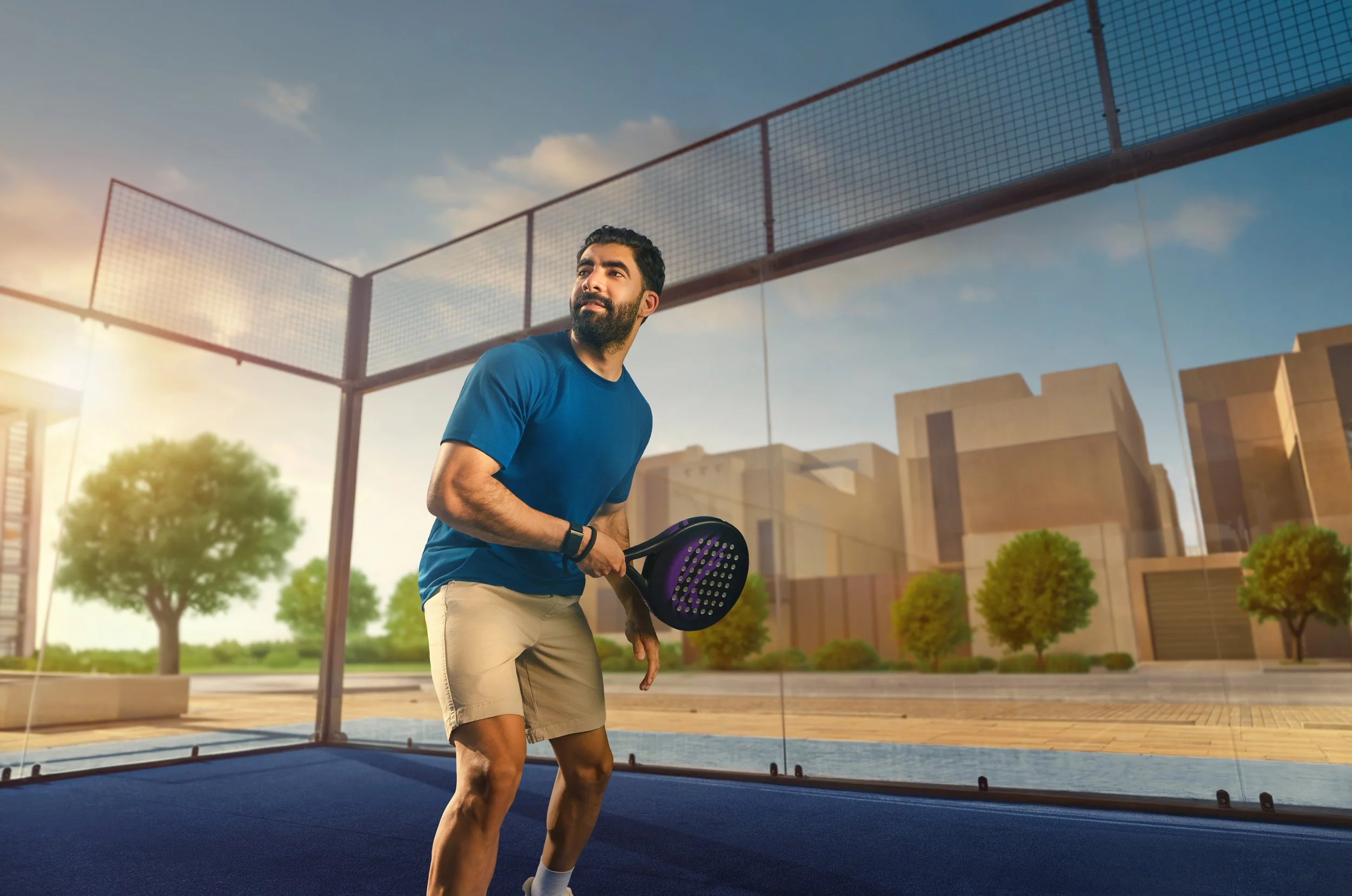 A man playing pickleball indoors near large glass windows with a cityscape background.