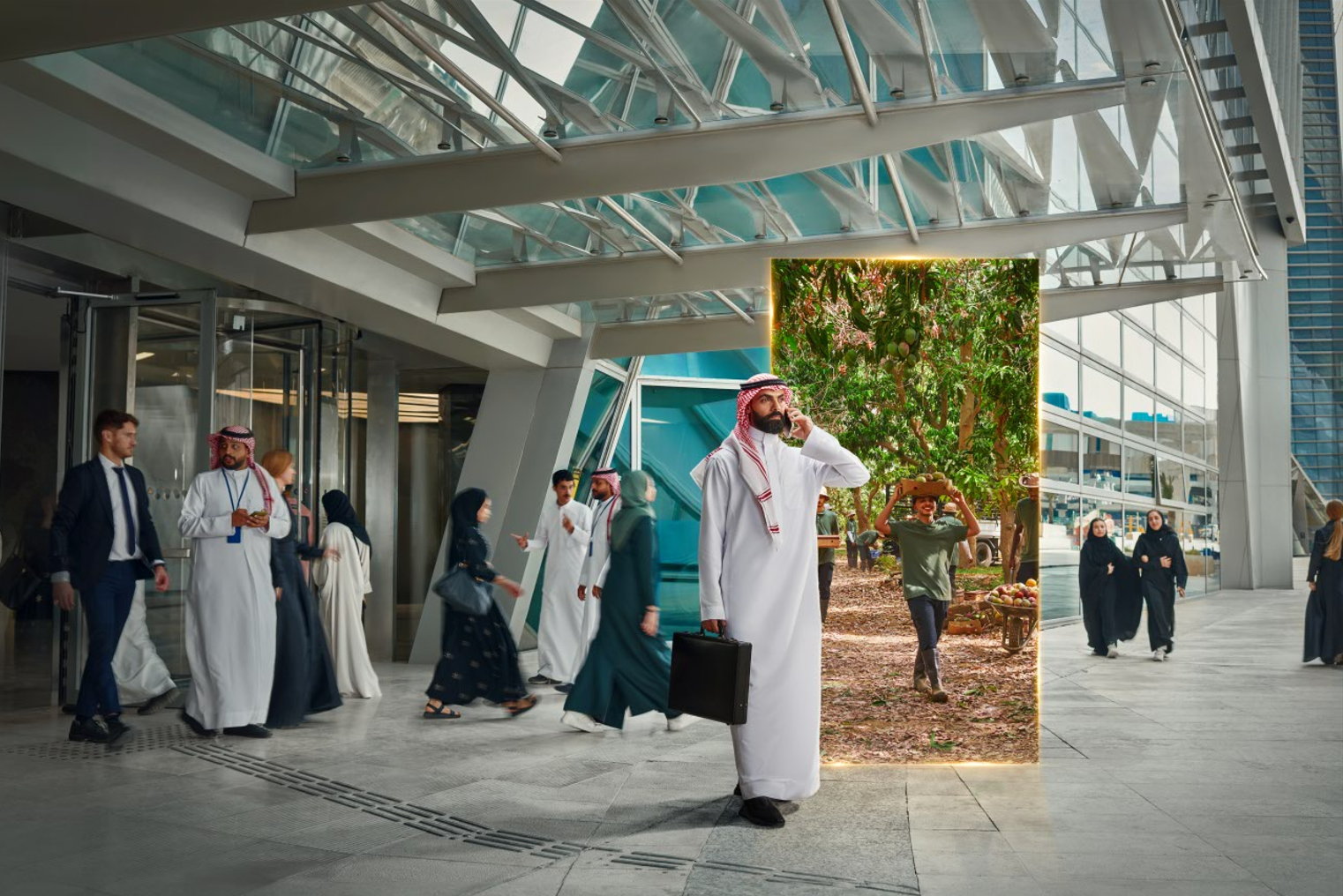 People walking outside a modern building, with a digital display showing a lush green tree scene, in an urban setting.
