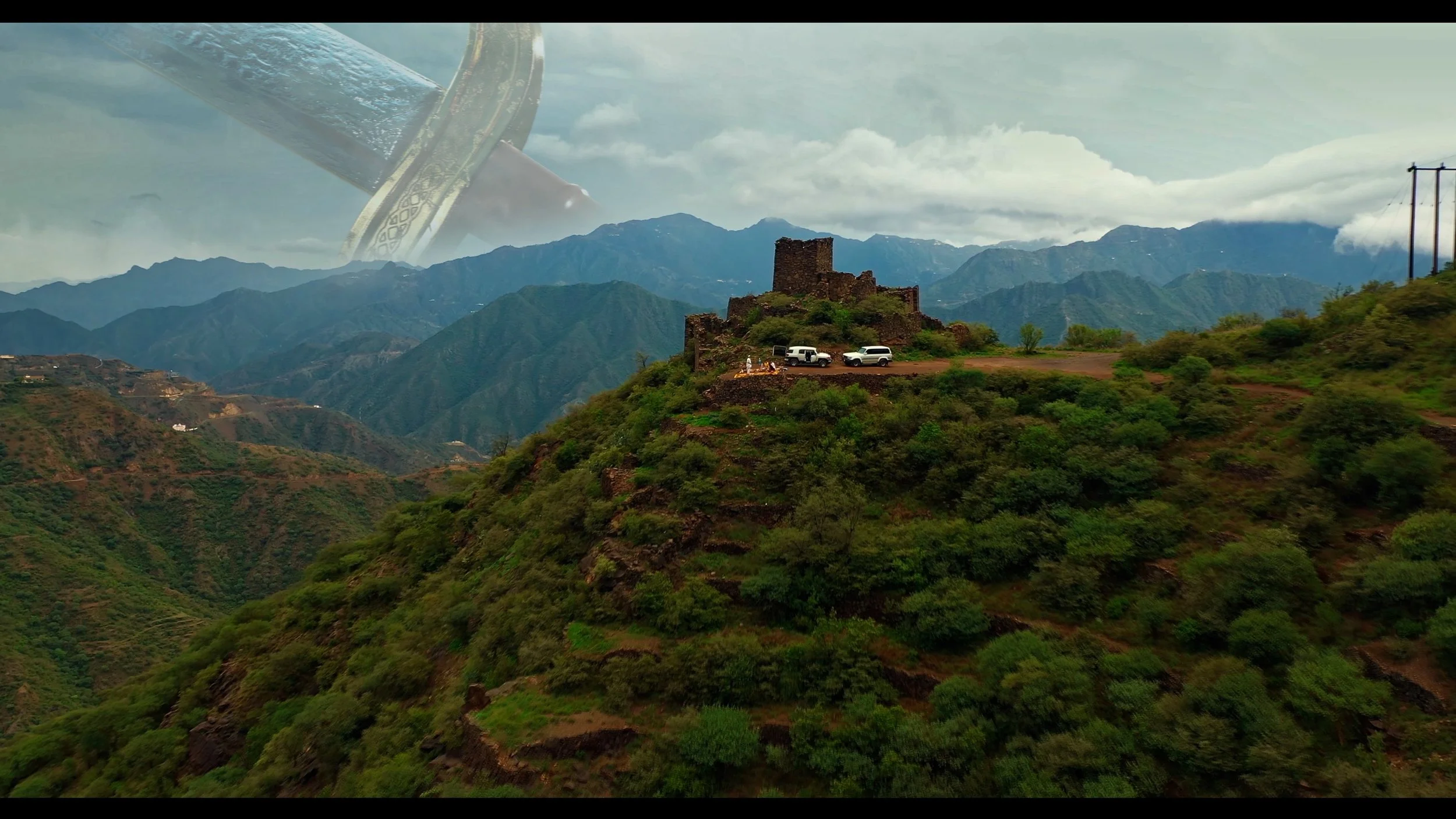 A hilly landscape with lush green vegetation and ancient ruins on top of a hill, with three white vehicles parked nearby. Overlaid is a faint giant sword in the sky with clouds in the background.