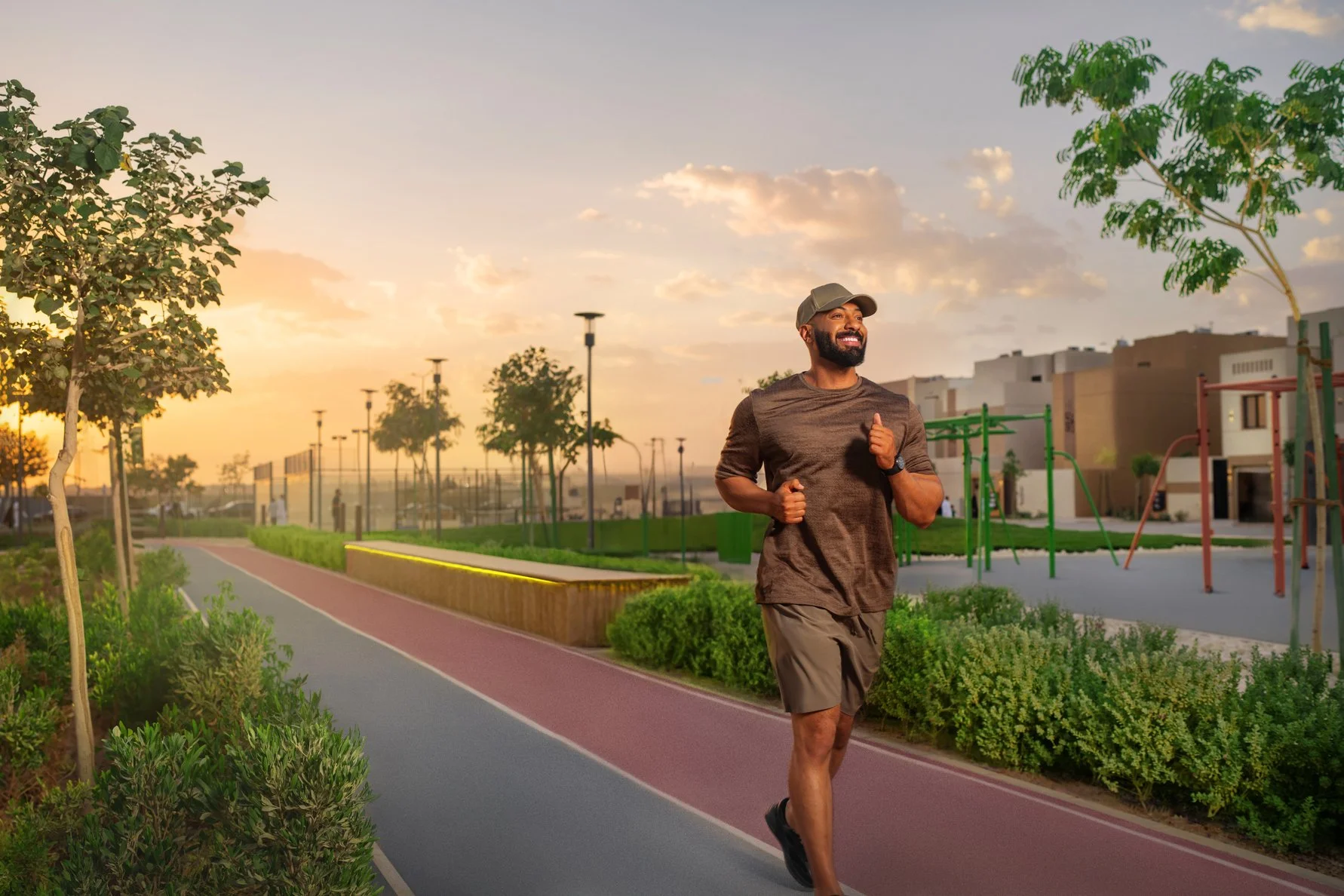 A man jogging on a park trail during sunset, with trees, bushes, and playground equipment in the background.