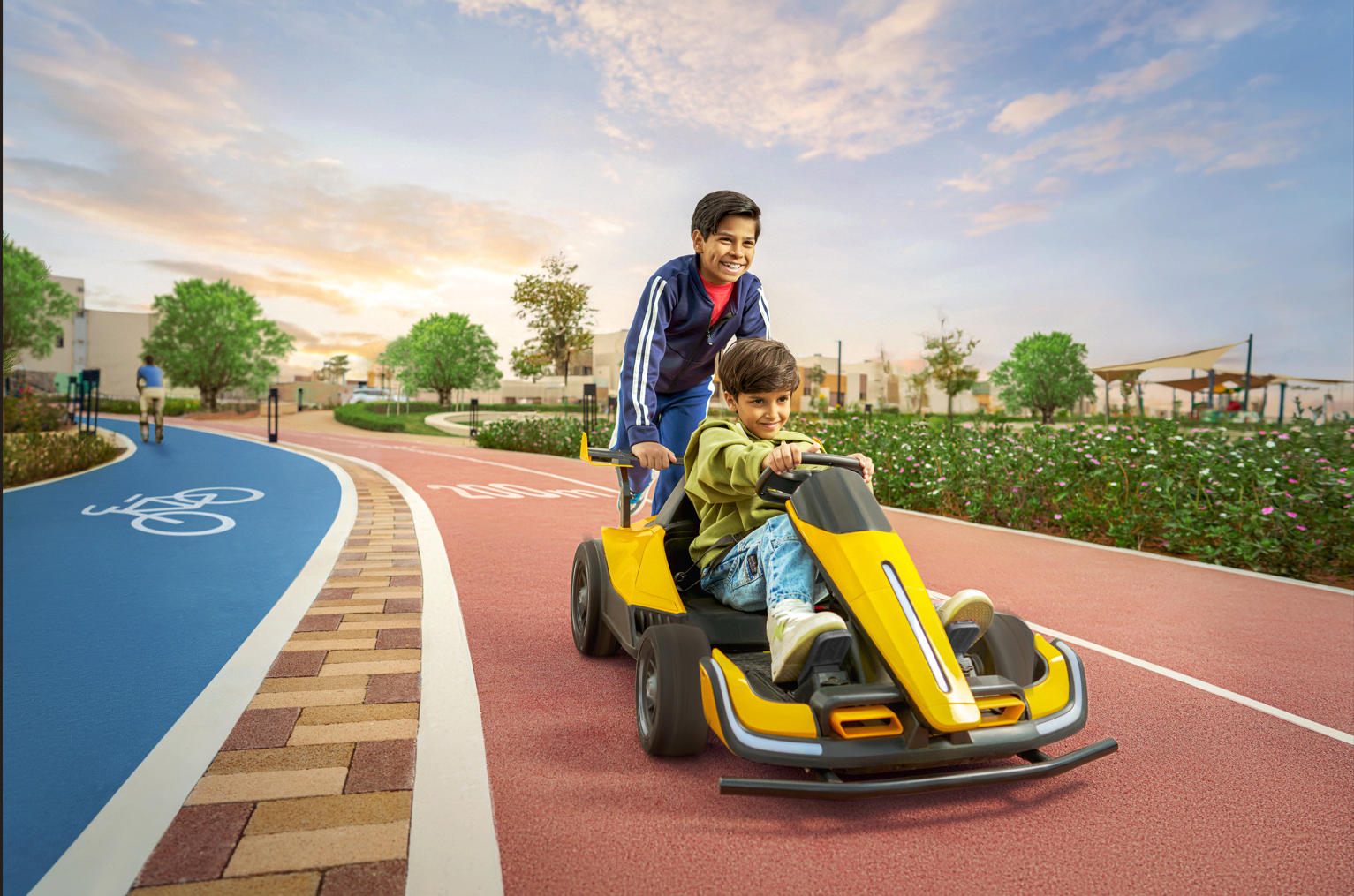 Two boys riding a yellow go-kart on a colorful bike path in a park during sunset.