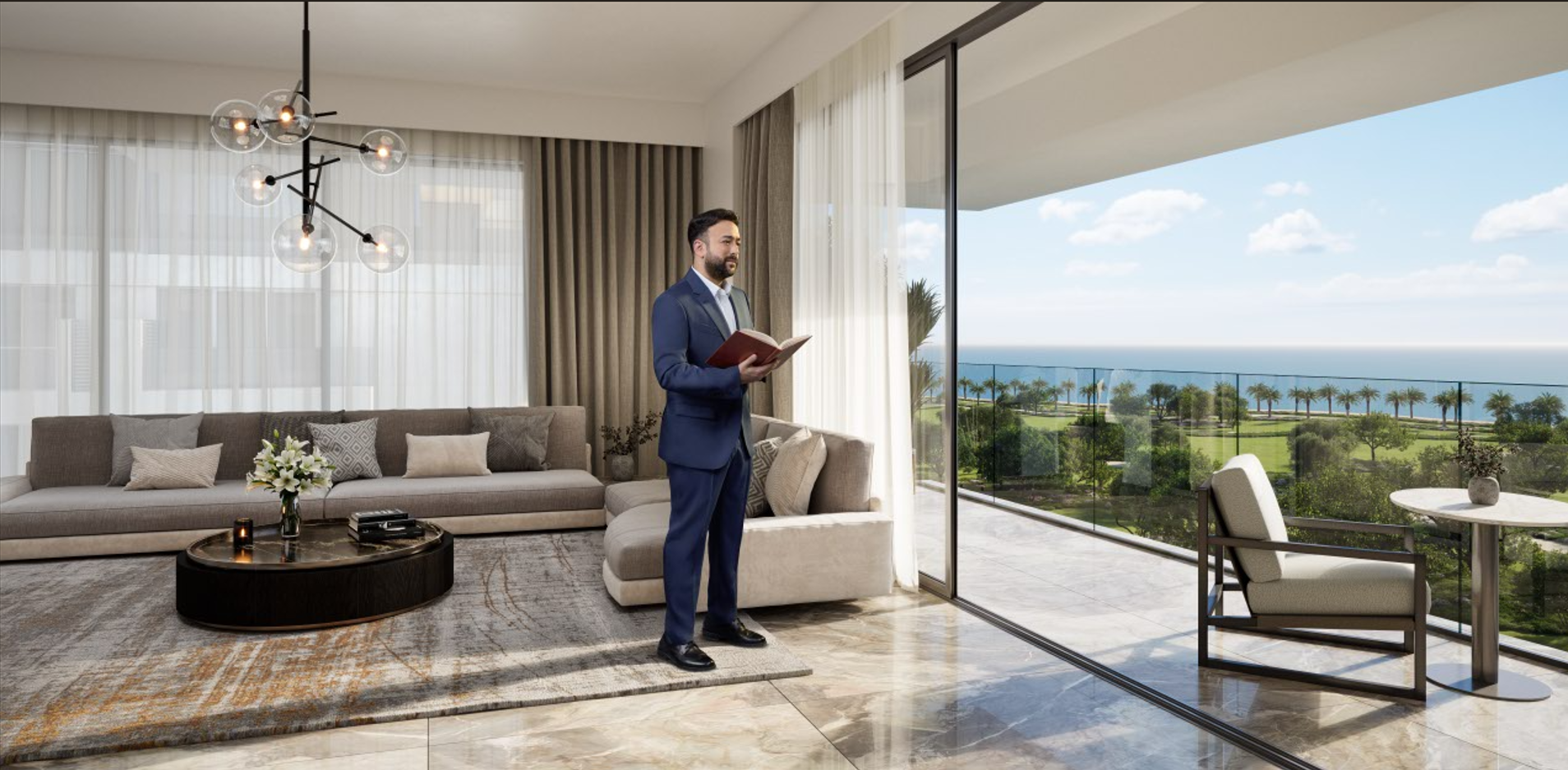 Man in a suit reading a book in a modern living room with large glass sliding doors that open to a balcony overlooking a landscape with trees and the ocean.