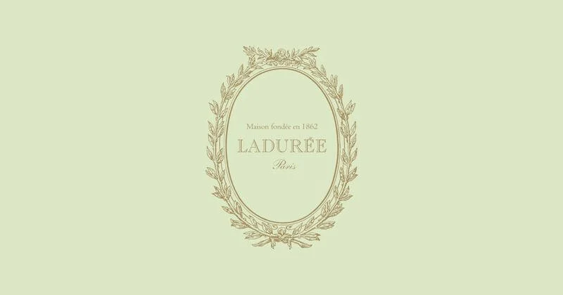 Light green background with an ornate oval frame in gold, featuring the text 'Maison fondée en 1862 Ladurée Paris' inside.