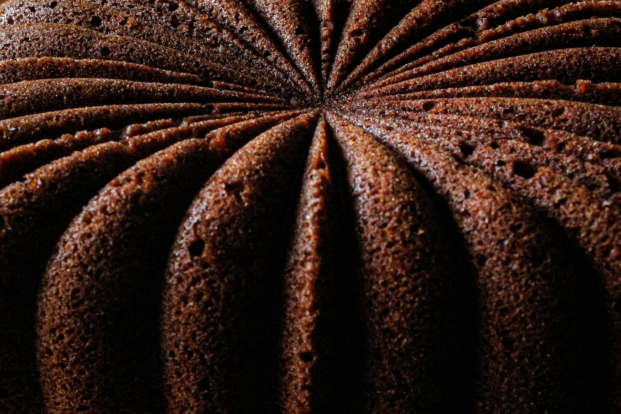 Close-up of a sliced chocolate Bundt cake with a textured surface and dark brown color.