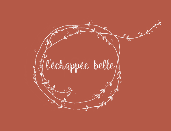 A brown background with a white, hand-drawn, circular vine wreath surrounding the French phrase 'l'échappée belle' in cursive text.