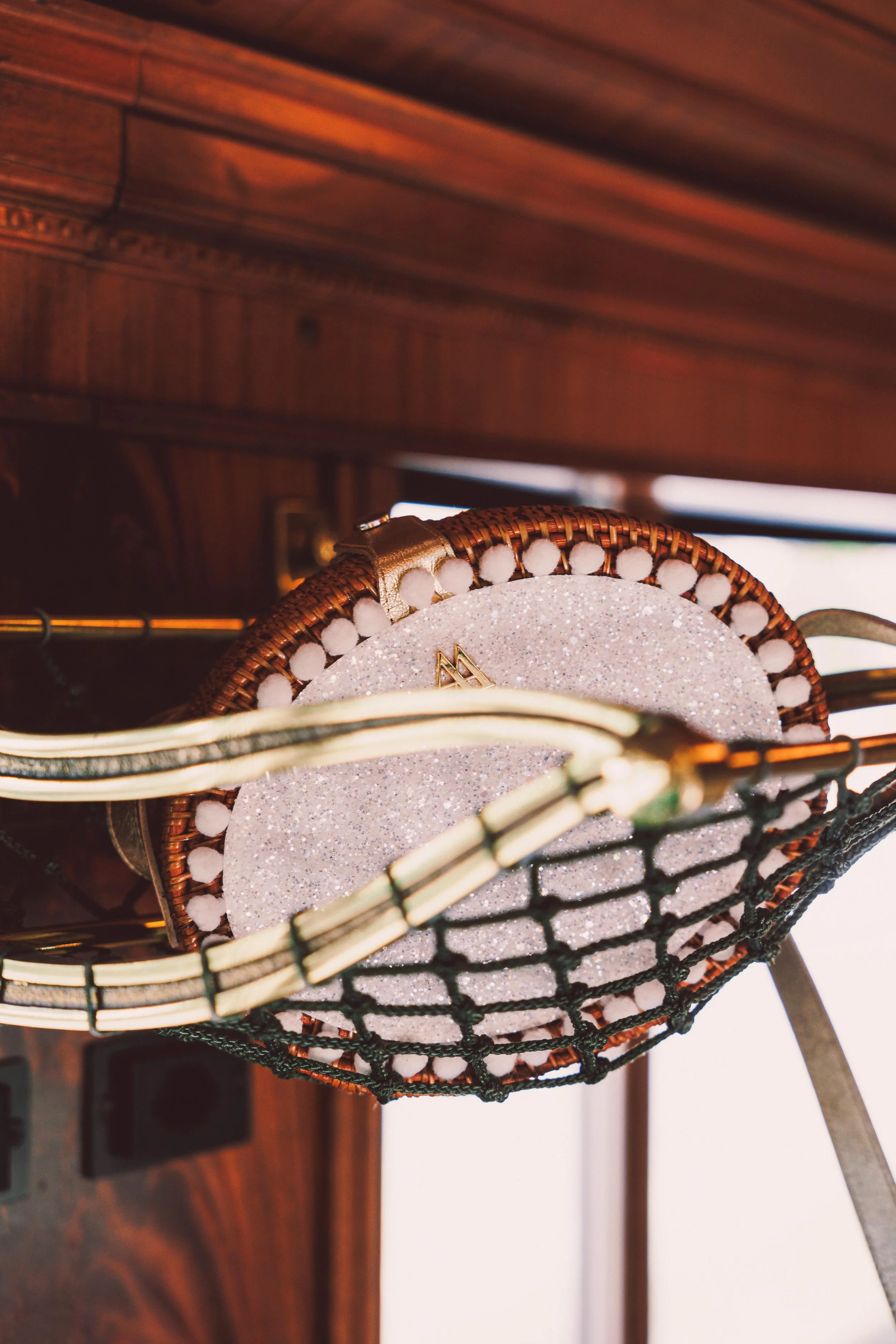Basket filled with circular items, possibly hats or small bags, with a glittery surface, resting on a wooden surface.