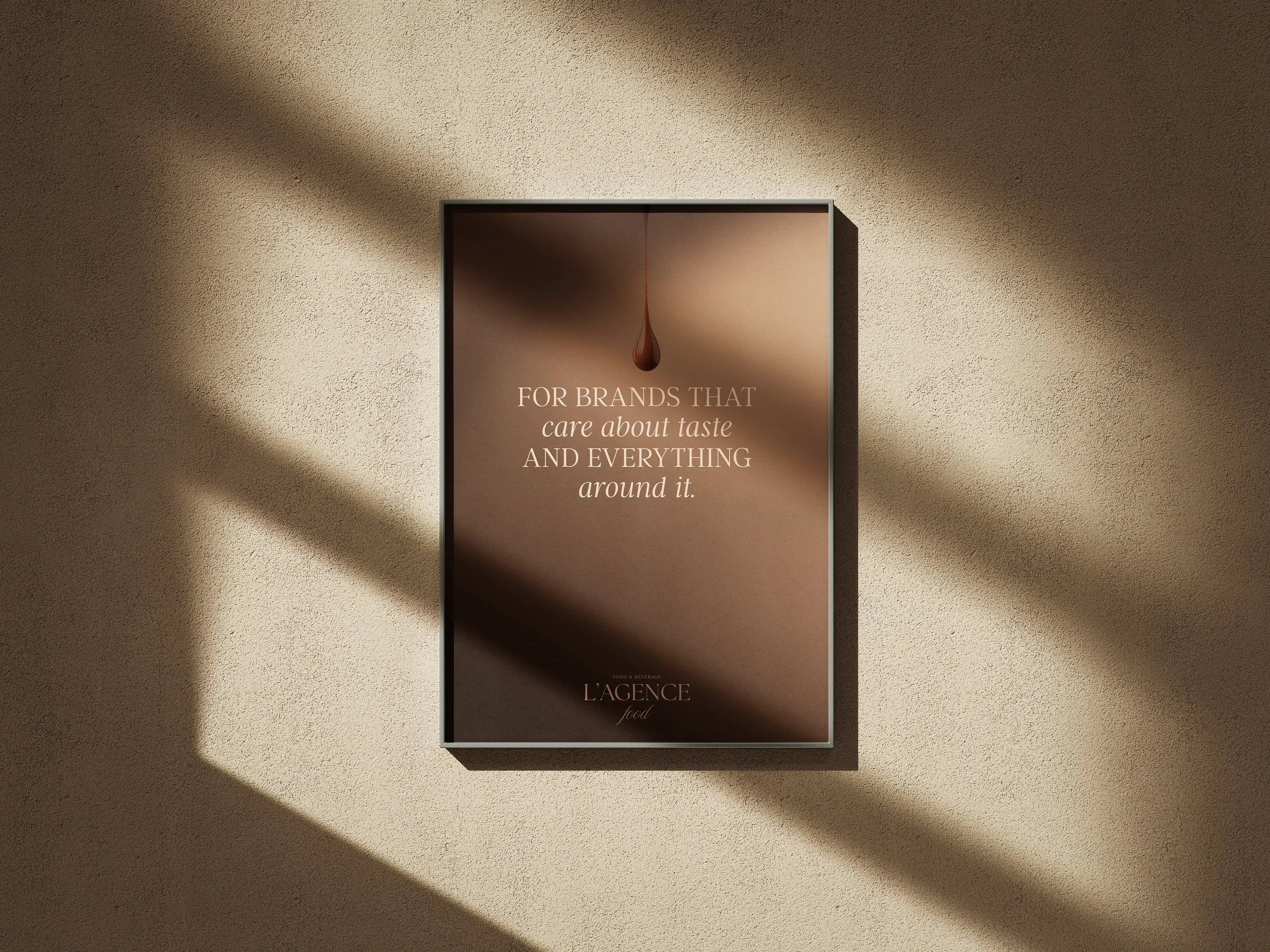 Poster with a brown background and a droplet at the top, featuring text that reads: "For brands that care about taste and everything around it." Beneath, the logo or brand name "L'Agence" is displayed.