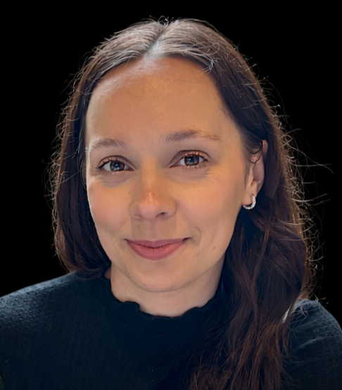 A woman with shoulder-length dark brown hair, light skin, wearing a black top, smiling with a black background.