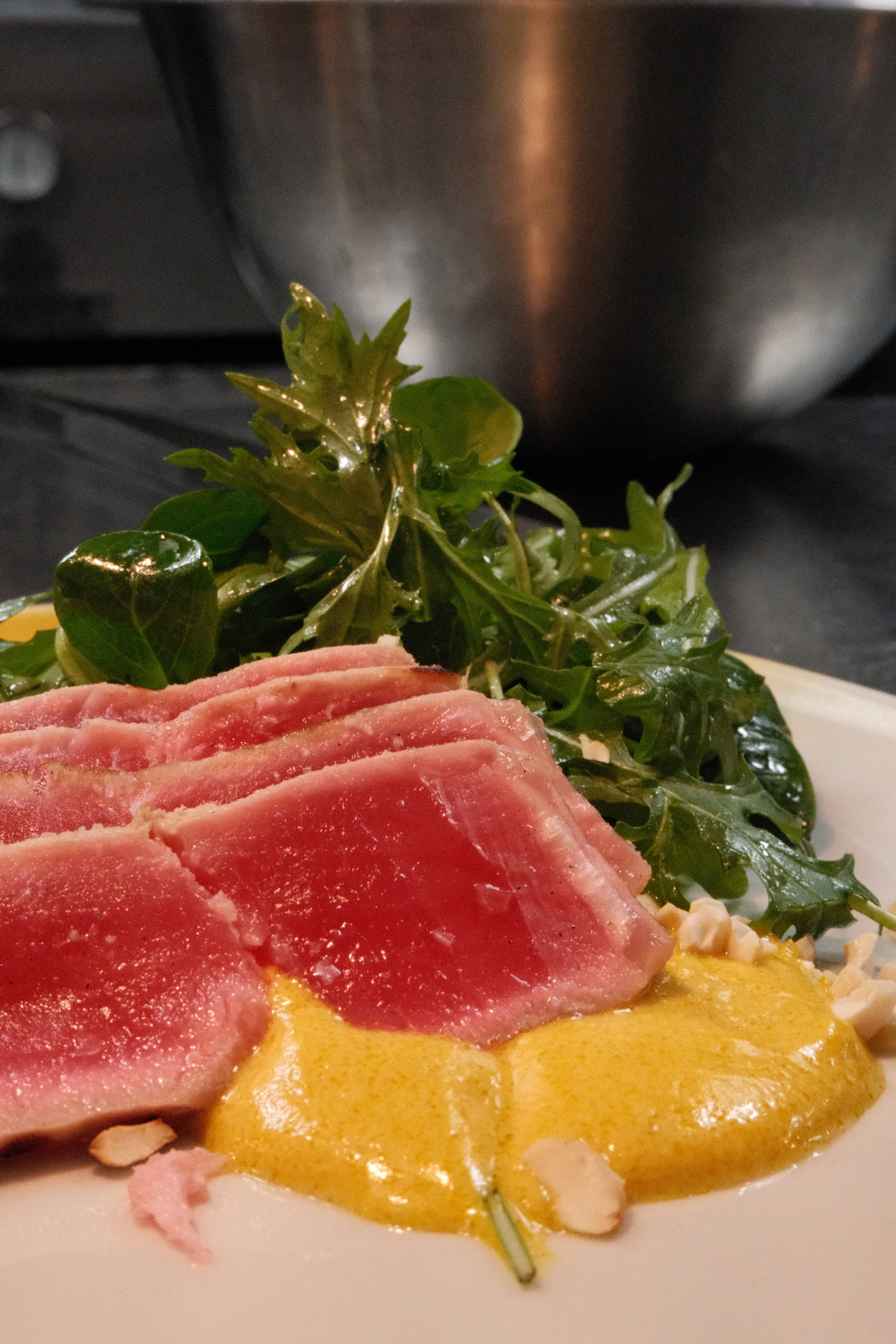 Tynnskåret rått kjøtt med sennepssaus og grønn salat på en tallerken.