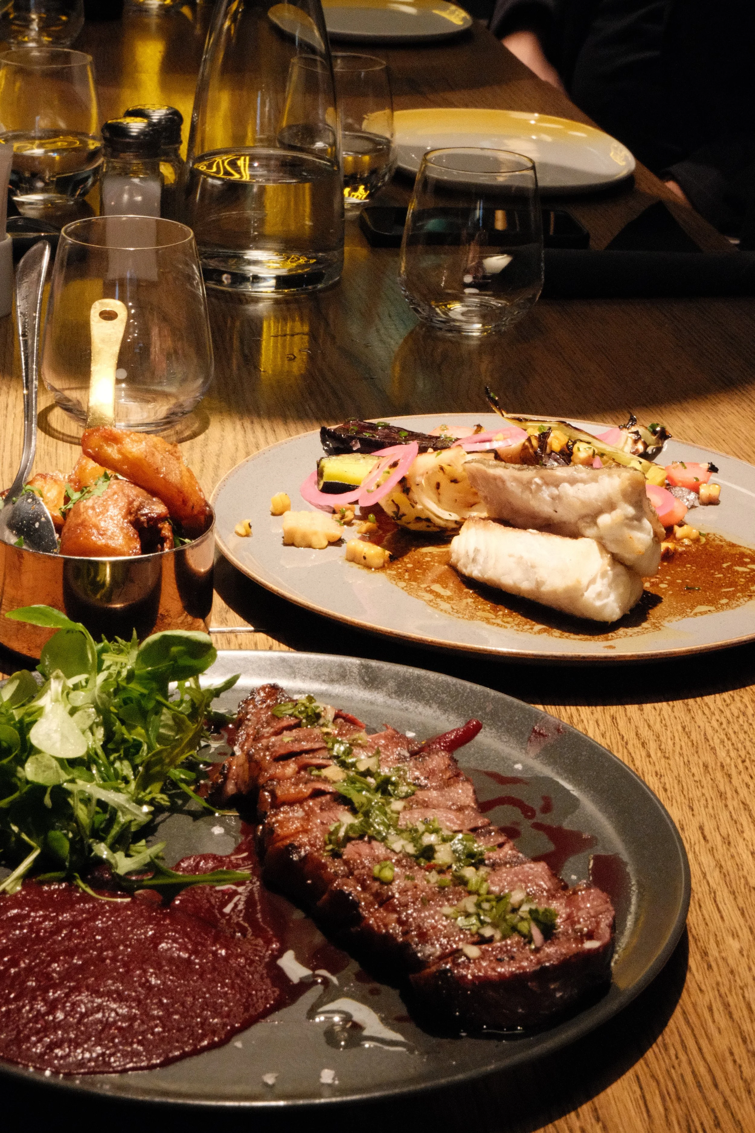 Bilder av en middag med stekt kjøtt, grønnsaker, og fisk, servert på en restauranten.