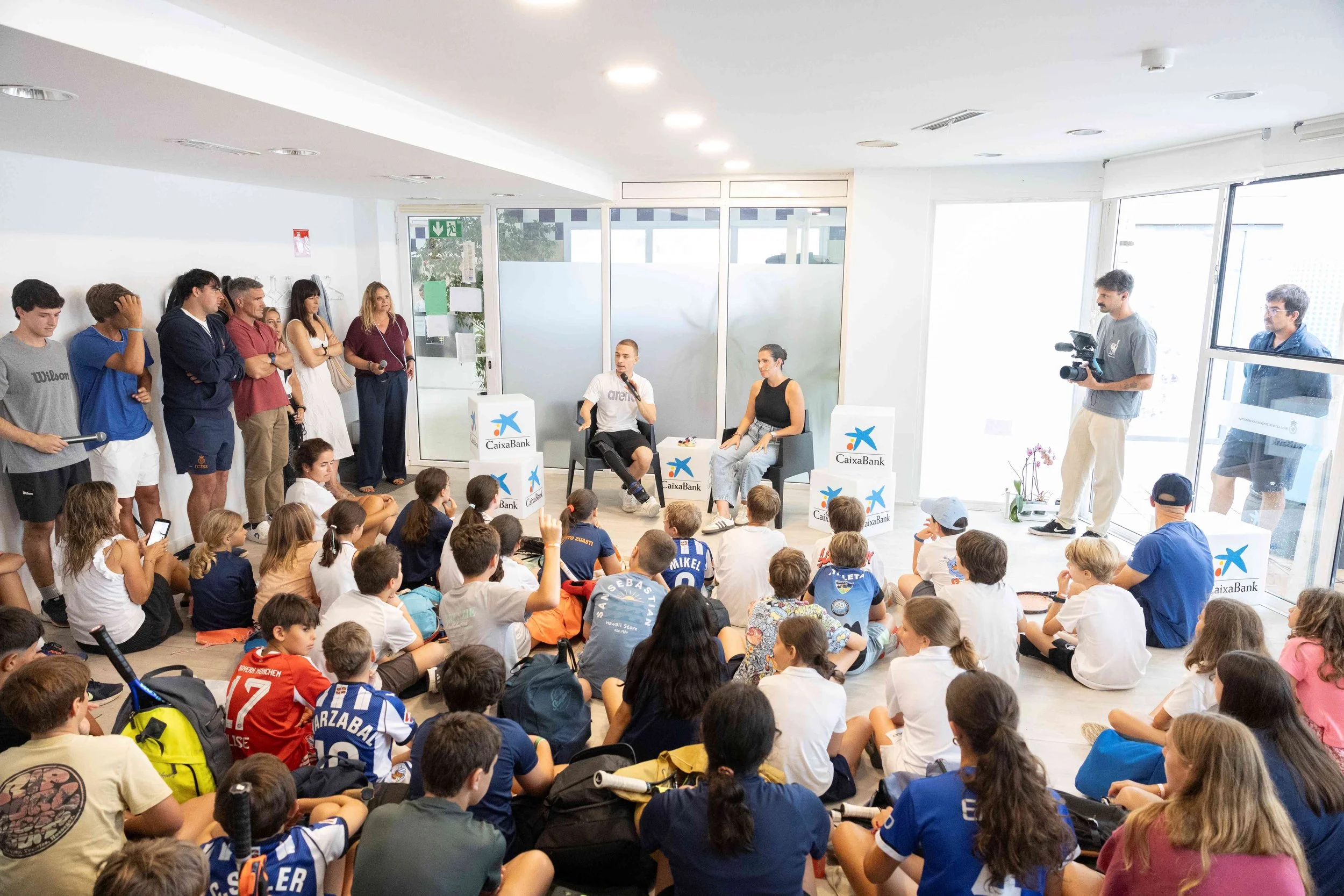 Carmen González dinamizando la jornada de Empower Kids de CaixaBank con el paralímpico Iñigo Llopis en el Tenis de San Sebastián