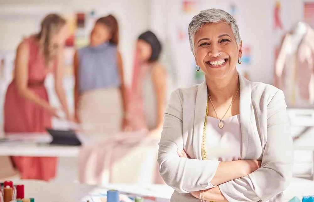 A woman smiling with folded arms with a team of women behind her