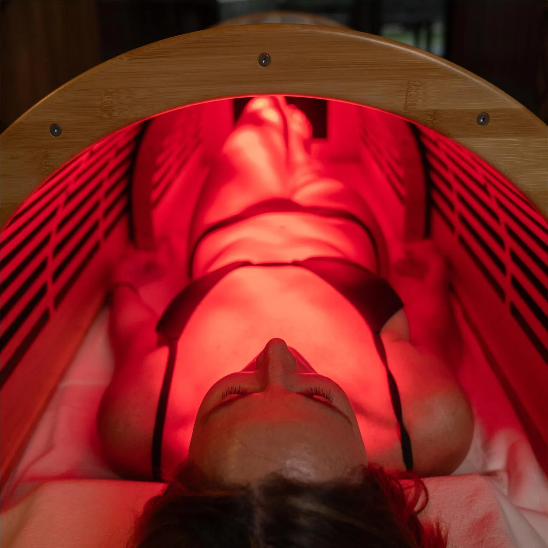 Une personne allongée sous une lampe de luminothérapie rouge, dans un cadre de spa ou de soin thérapeutique.
