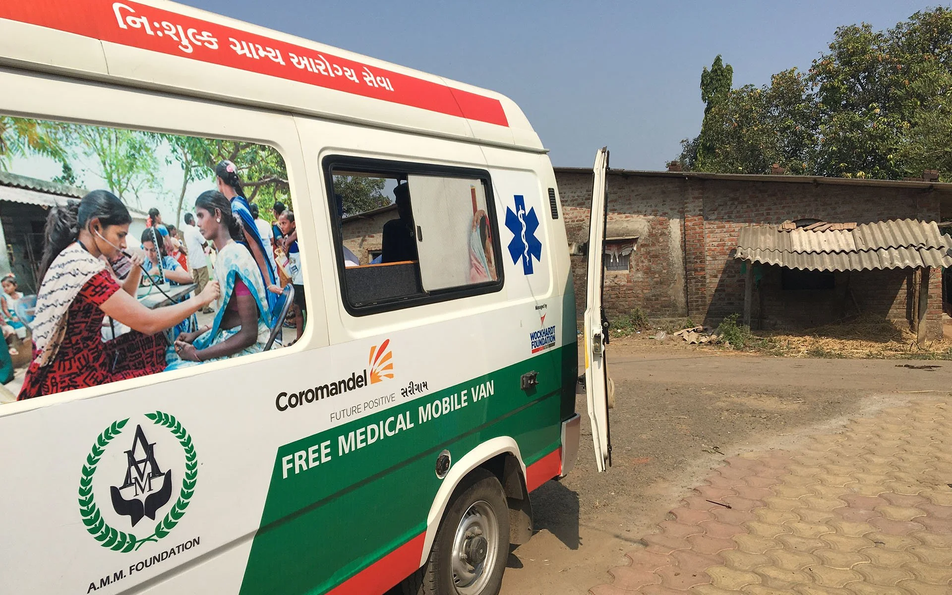 A mobile medical van providing free medical services. The van has an image of children and medical symbols on its side, with text indicating it is part of a foundation offering free medical care.