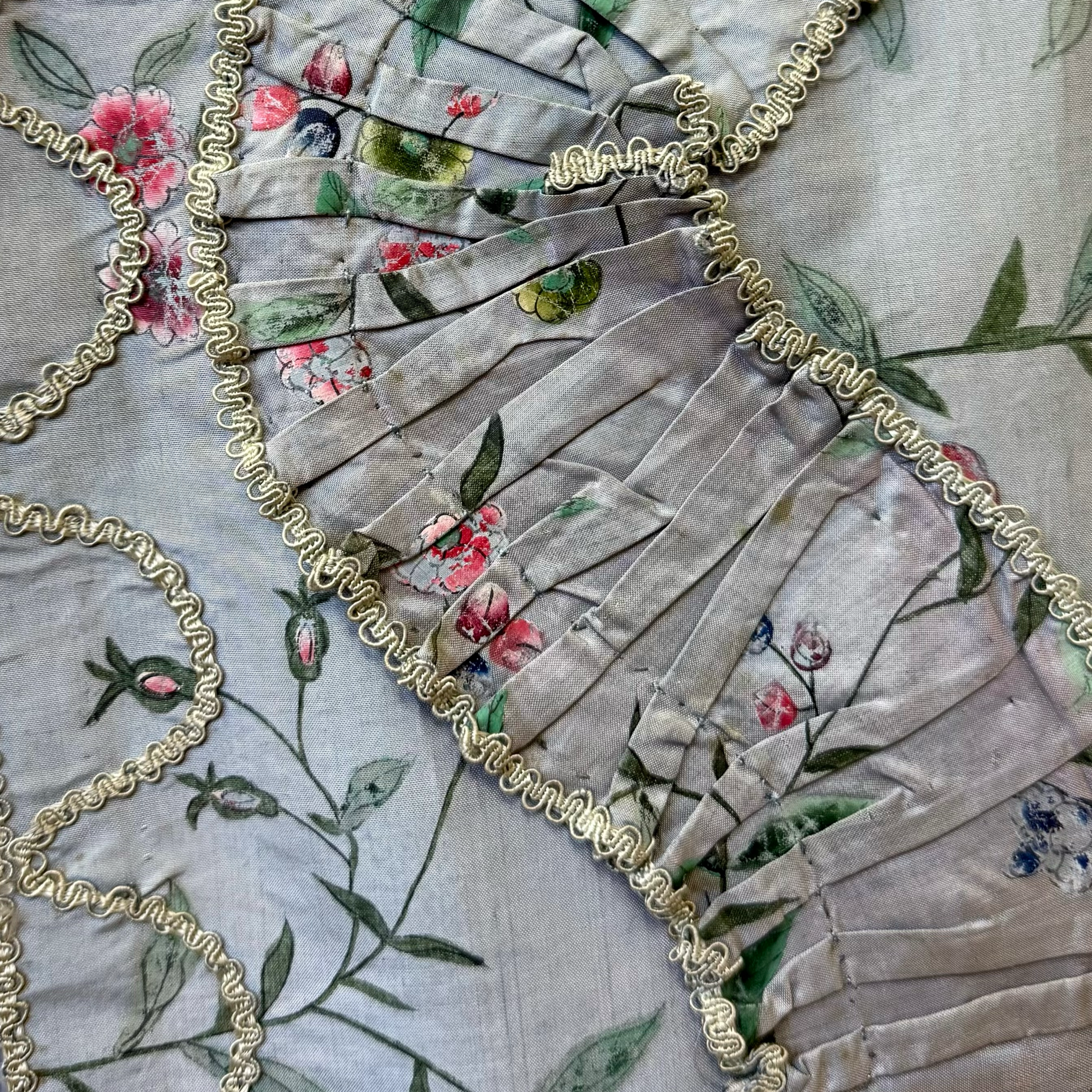 Close-up of floral-patterned fabric with decorative ribbon and embroidery.