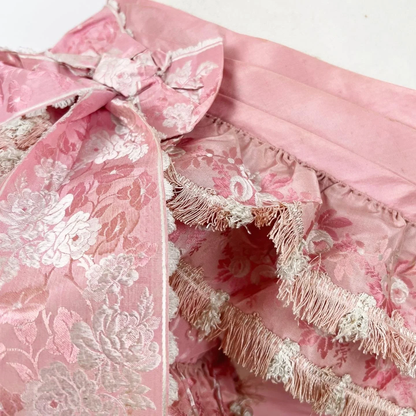 Detail, pink silk ballgown circa 1860, trimmed with brocade ribbon and fringe 