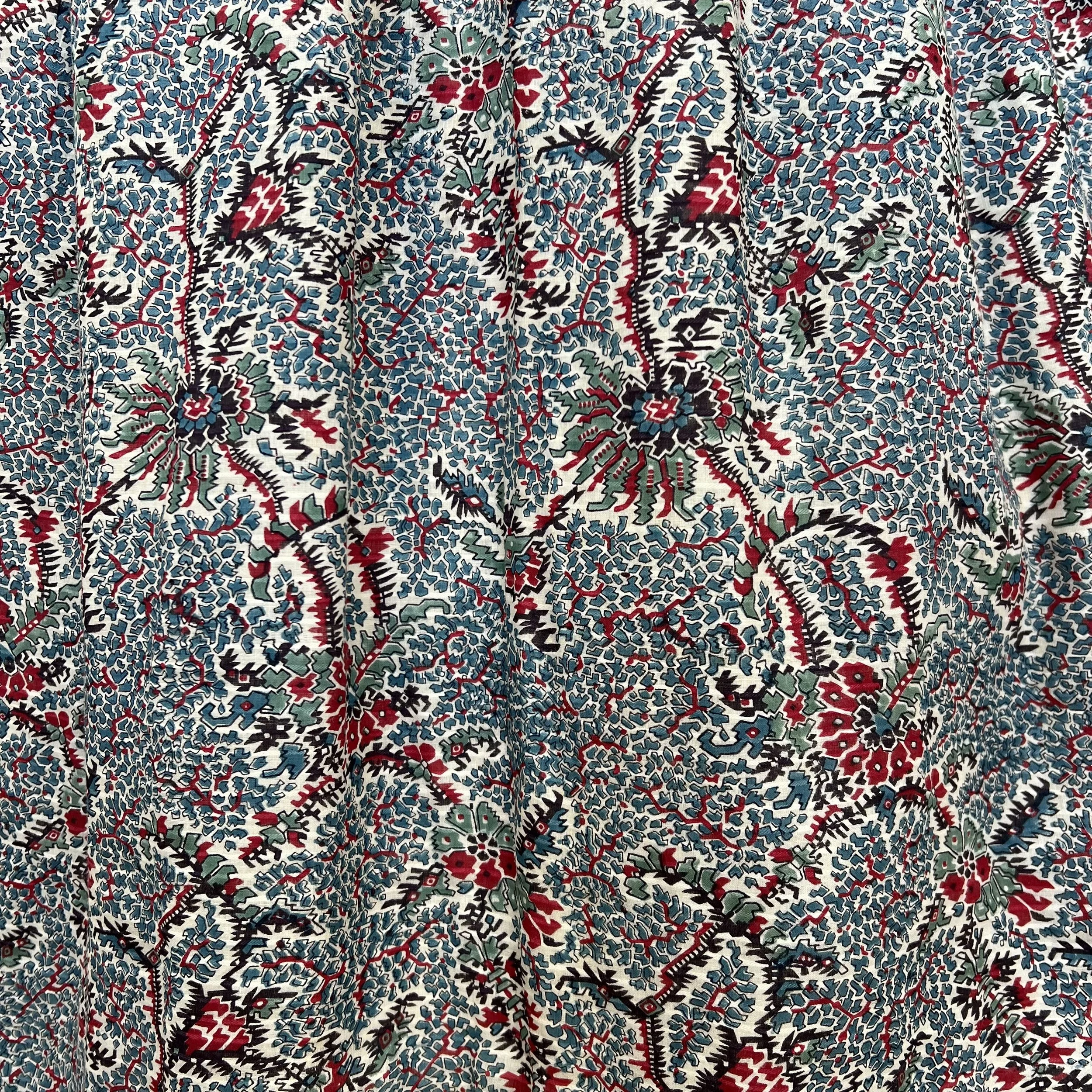 Close-up of a fabric with a complex, colorful floral pattern featuring red, blue, green, black, and white colors.