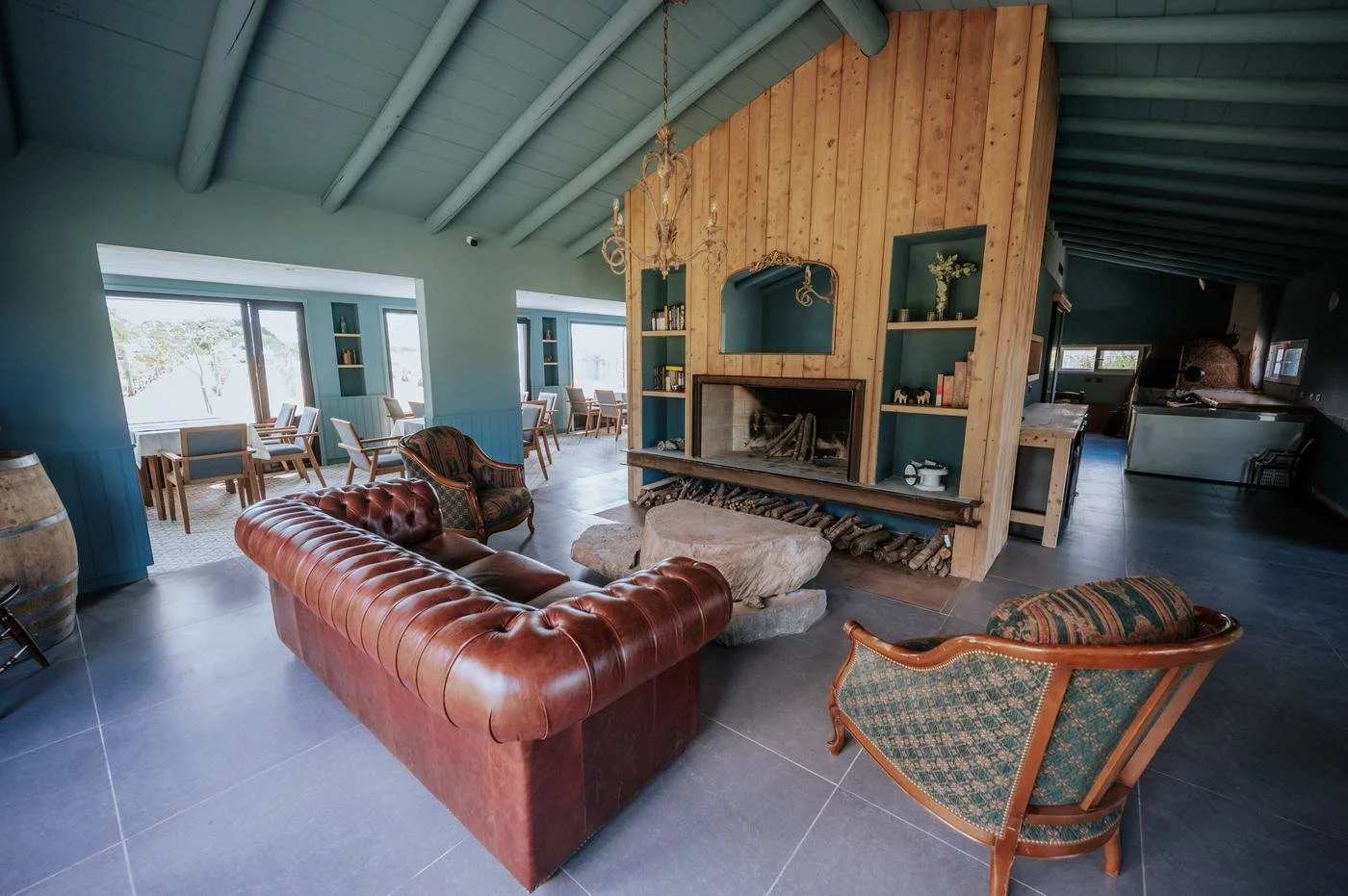 Salón con chimenea, sillones de cuero y paredes azul petróleo