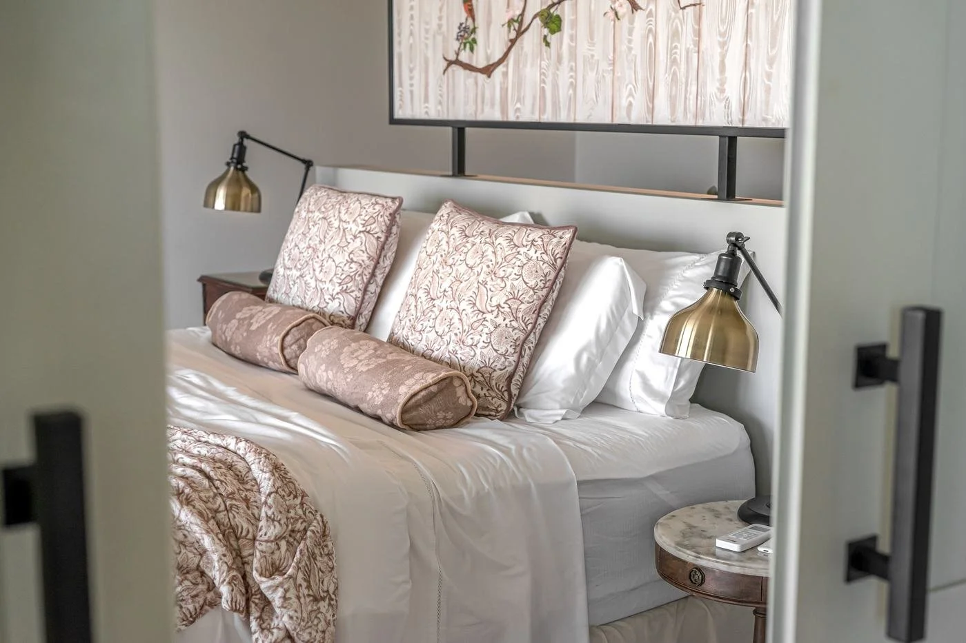 Cama king size con almohadones y lámparas de bronce