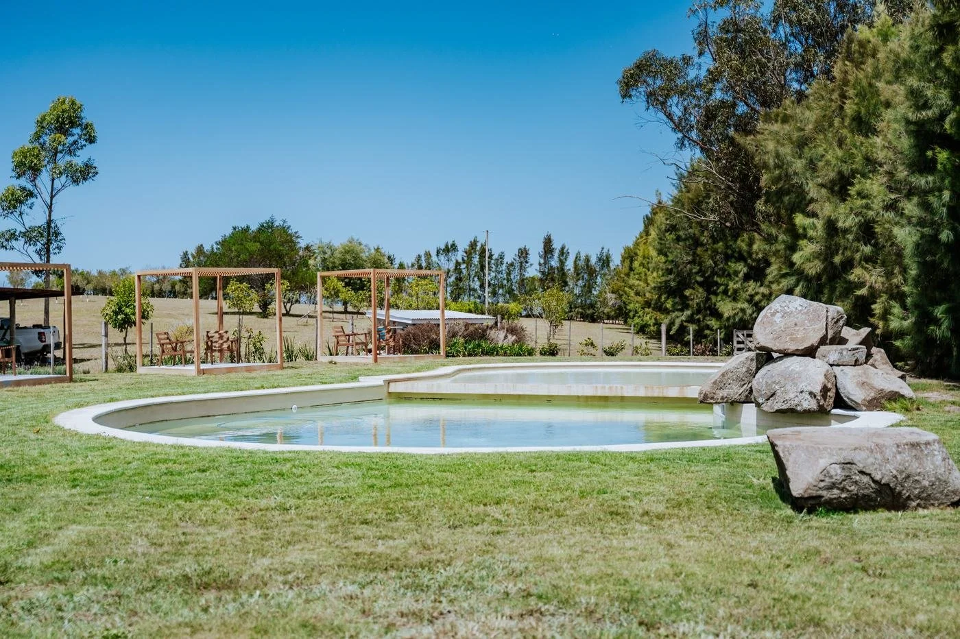 Piscina rodeada de césped y pérgolas