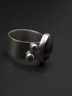Handcrafted sterling silver wide-band ring with a round tiger's eye cabochon in a raised bezel accented with decorative silver balls, handmade by Jennifer Morris