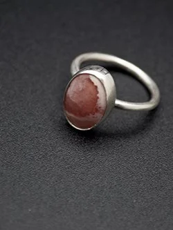 Handmade sterling silver ring with an oval pink rhodochrosite cabochon featuring natural white banding, bezel-set on a simple round band, by Jennifer Morris