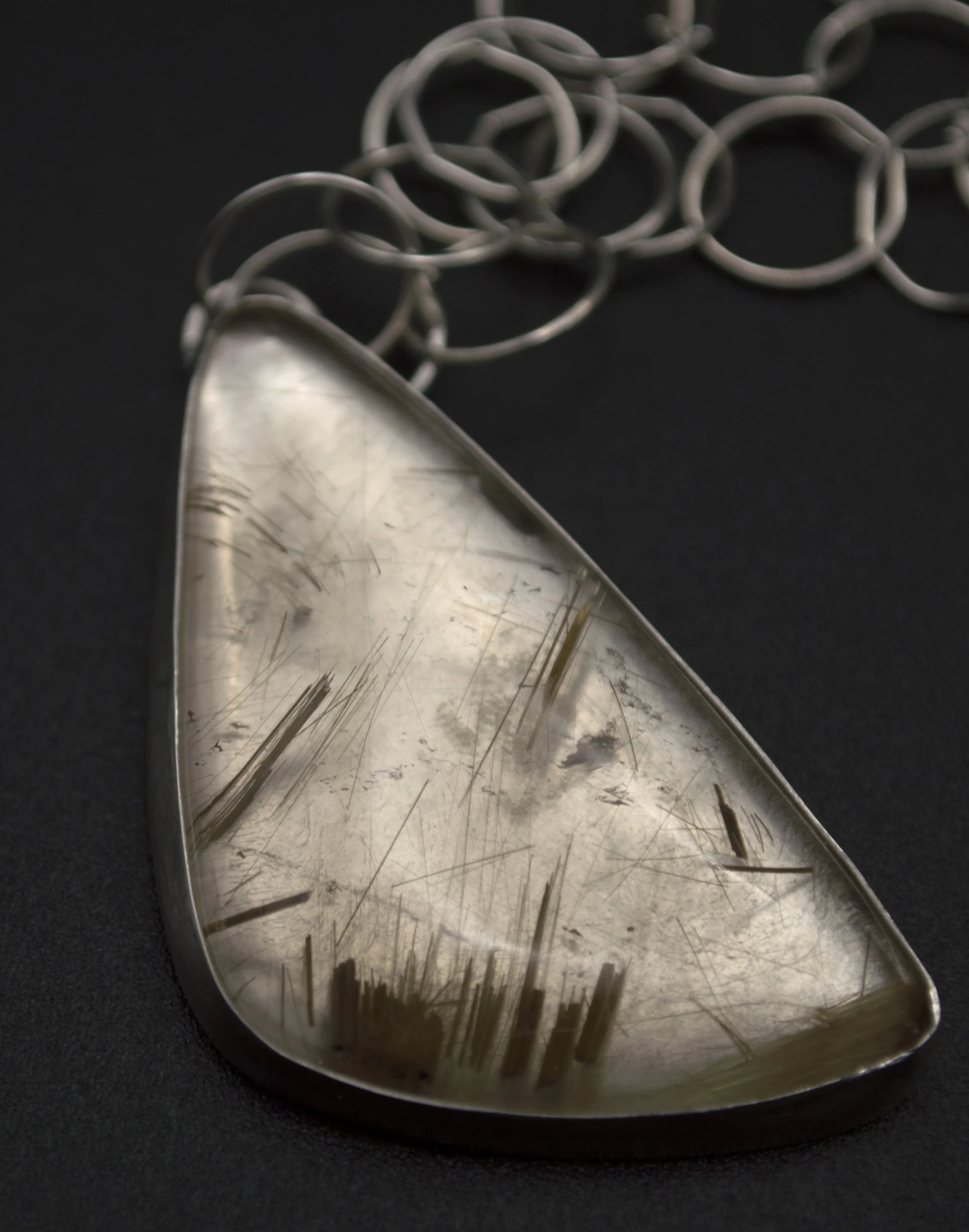 Handmade sterling silver statement pendant with a large triangular rutilated quartz cabochon showing golden needle-like inclusions, on a handcrafted open-link chain, by Jennifer Morris