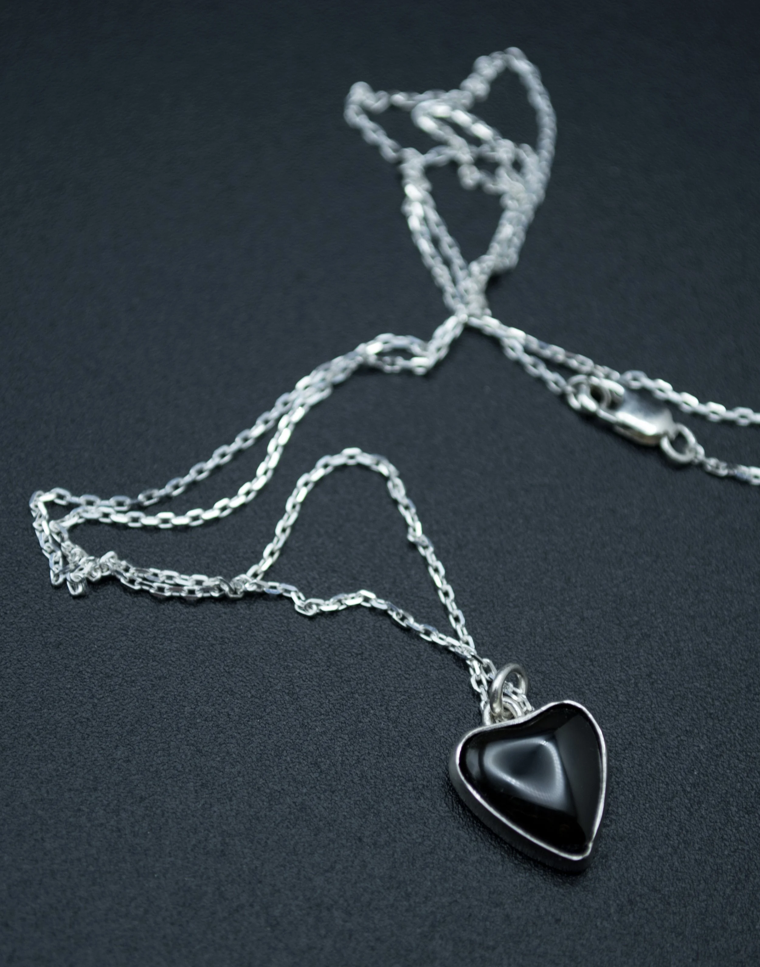 Handmade sterling silver necklace with a glossy black onyx heart-shaped pendant in a polished bezel on a fine silver chain, handcrafted by Jennifer Morris