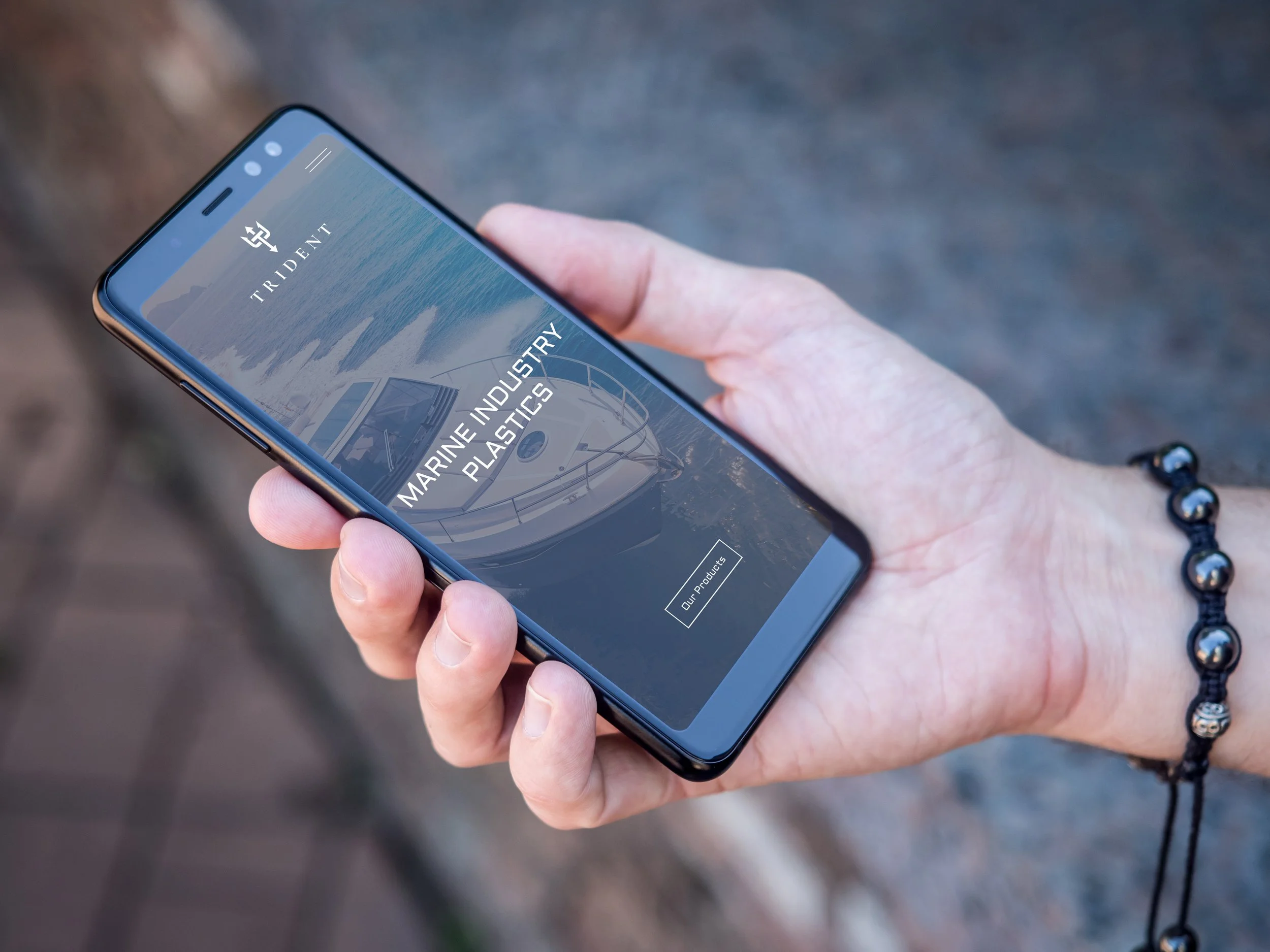 An image of hand holding mobile Trident website.