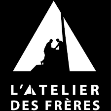 Silhouette of two men sitting inside a tent, with a campfire between them, and the text "L'Atelier des Frères" below.