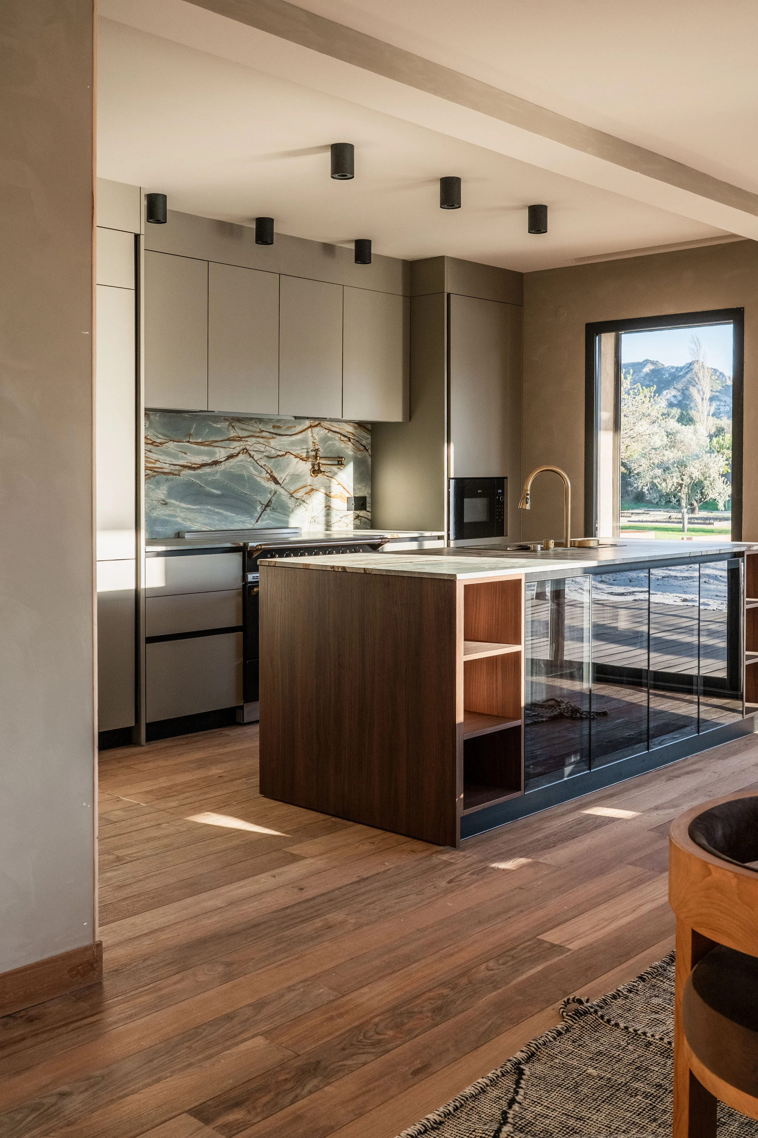 Modern kitchen with beige cabinets, marble backsplash, wooden island, and large window with mountain view