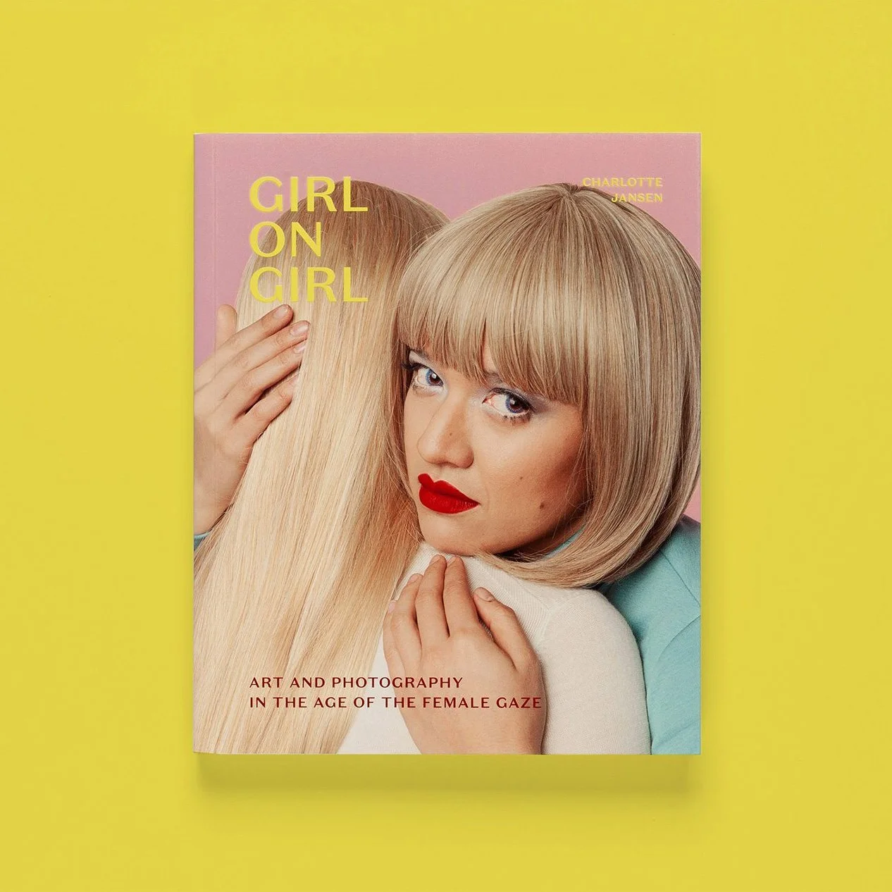 Book cover titled "Girl on Girl" by Charlotte Jansen featuring a woman with blonde bob haircut and lipstick embracing another person with long blonde hair against a pink background, with yellow background surrounding the book.