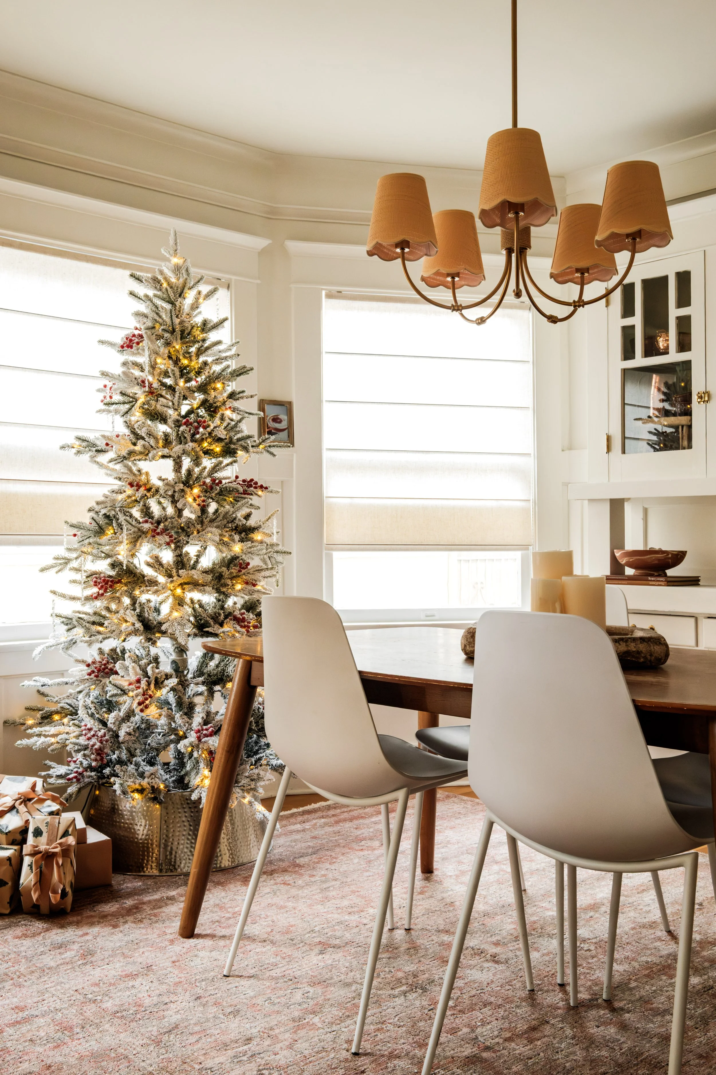 A decorated Christmas tree with lights inside a bright dining room with white walls and furniture.