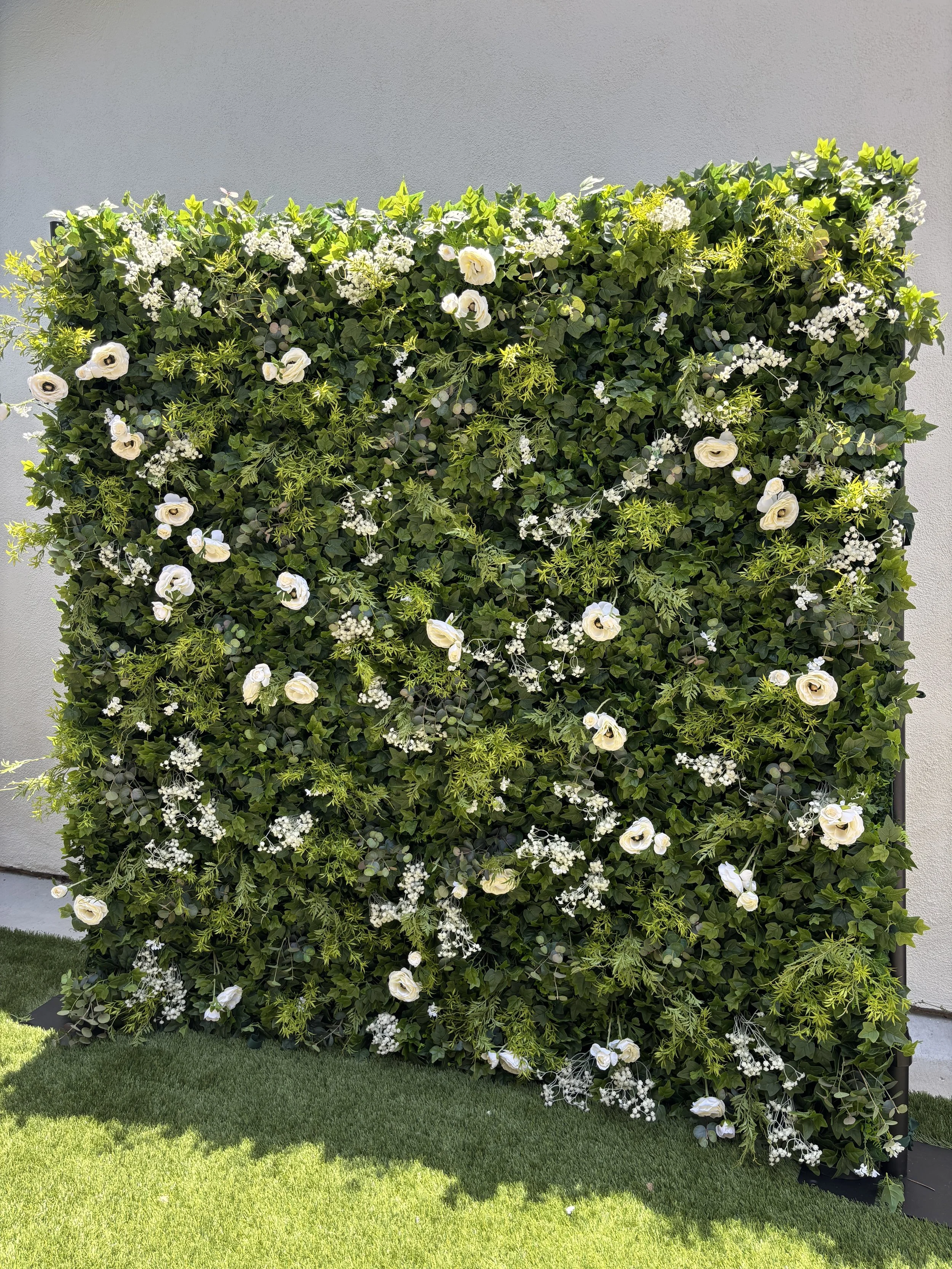 The Lola flower wall, a lush greenery and white floral backdrop available for event rentals in Orange County, CA.