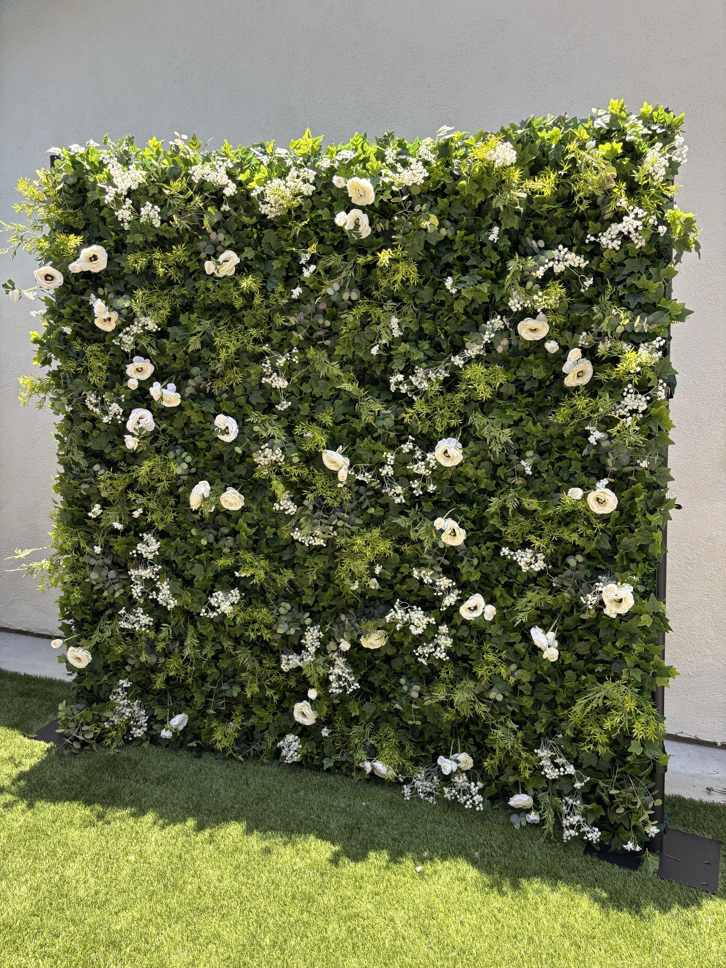 The Lola flower wall, a lush greenery and white floral backdrop available for event rentals in Orange County, CA.