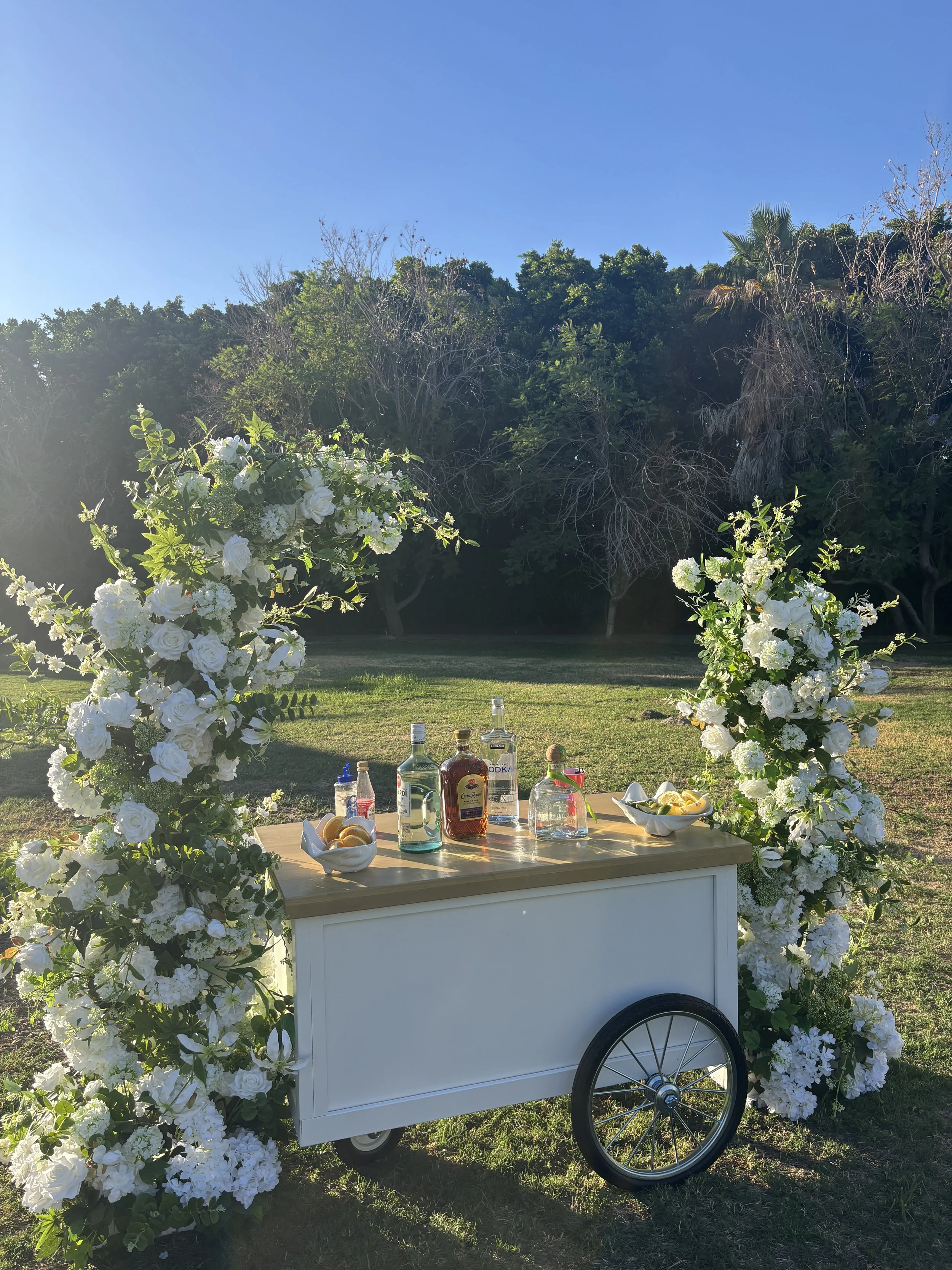 Styled floral and beverage display for an outdoor celebration by Two Suns Studio.