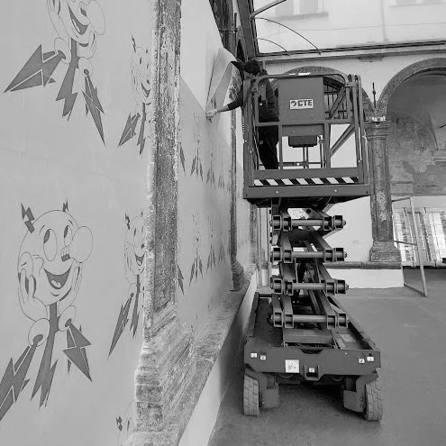 Operaio su piattaforma elevatrice che lavora su un murale con un personaggio animato grafico.