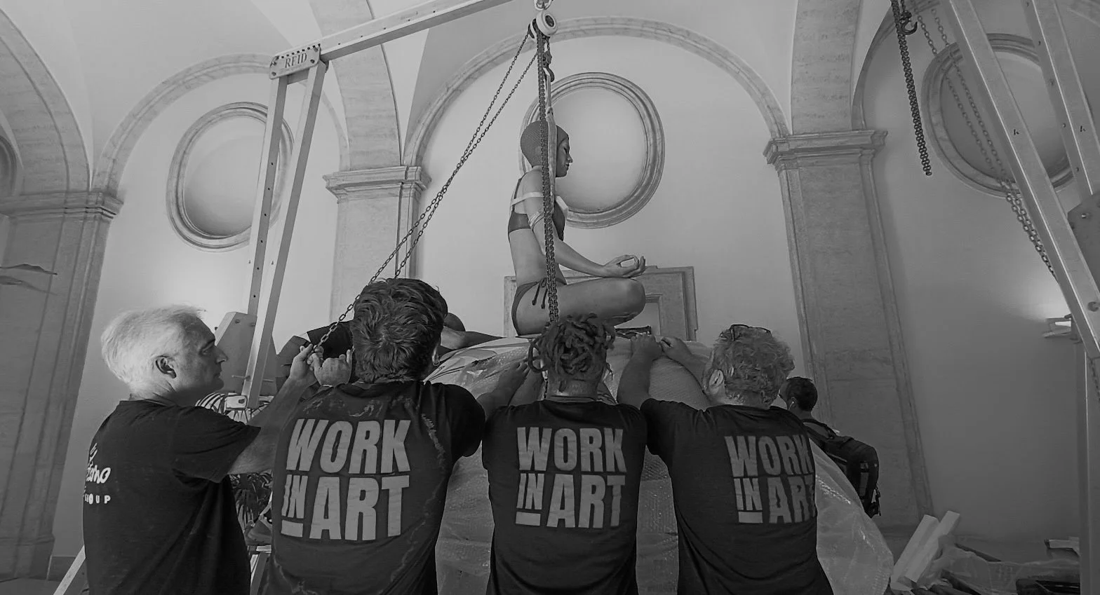 Operai che lavorano alla conservazione di una statua religiosa in un edificio storico.