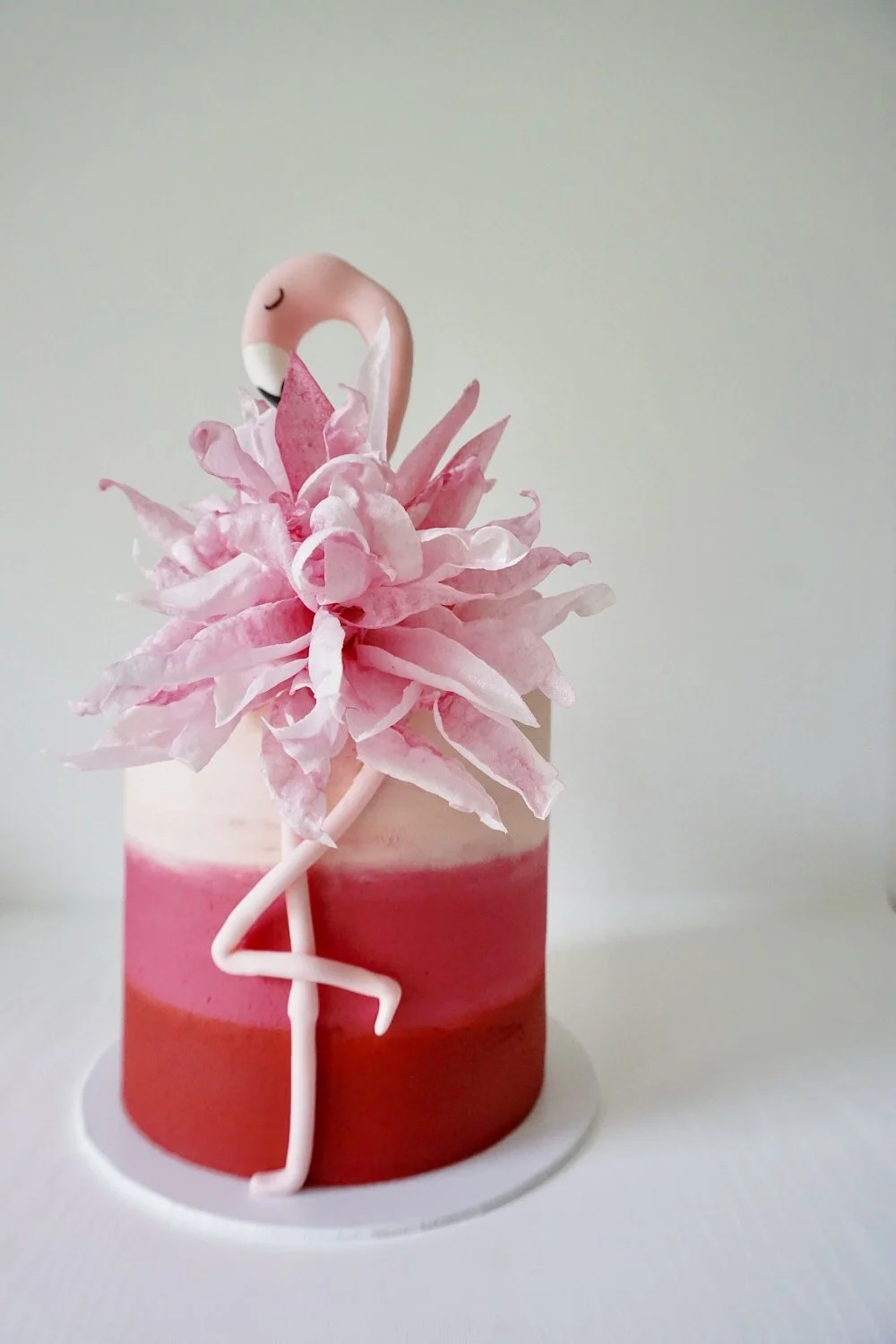 Pink flamingo cake with a pink flower decoration and flamingo topper.