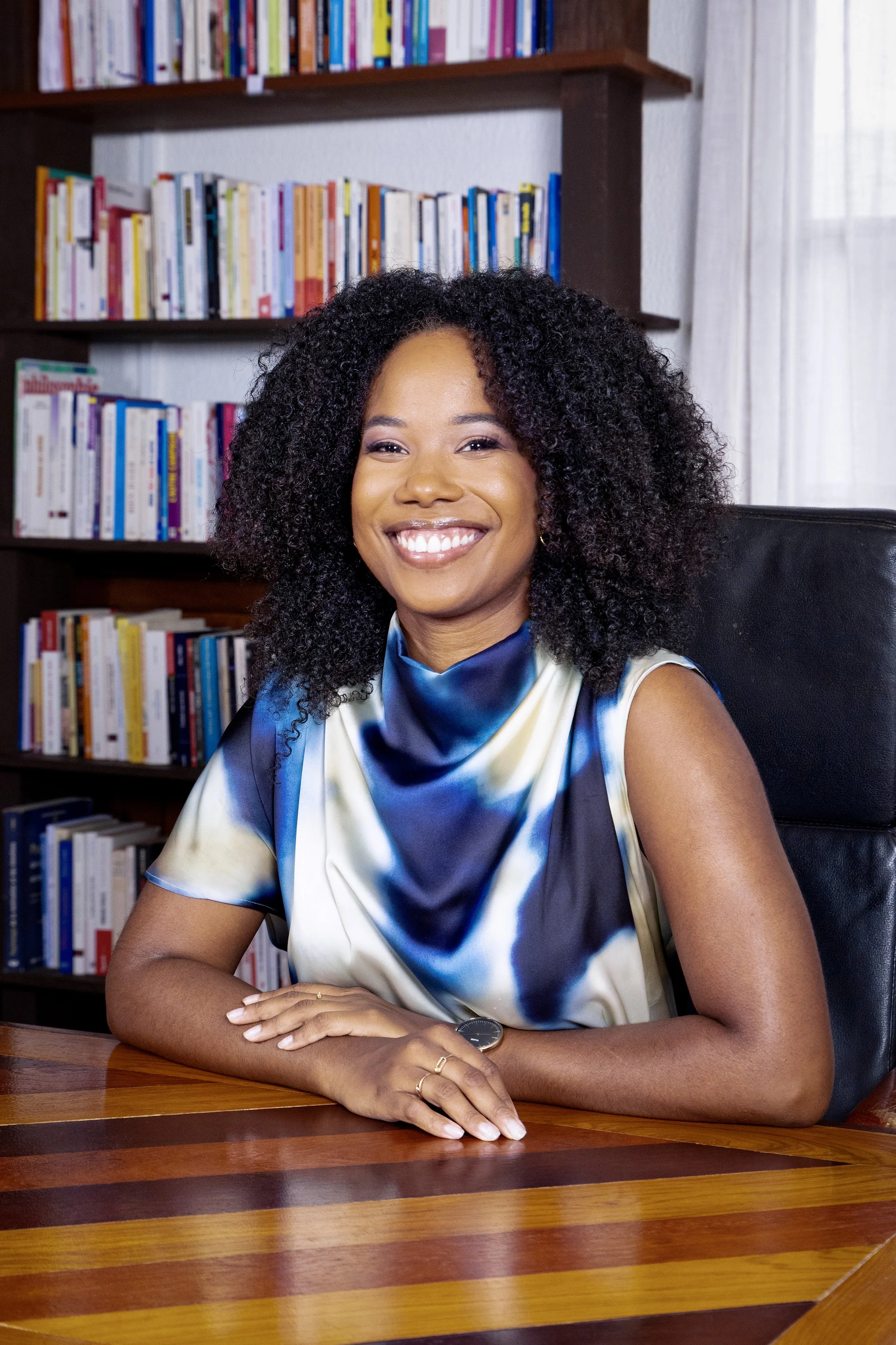 Avocate en cabinet juridique en Guyane, assise à son bureau avec bibliothèque de livres de droit.