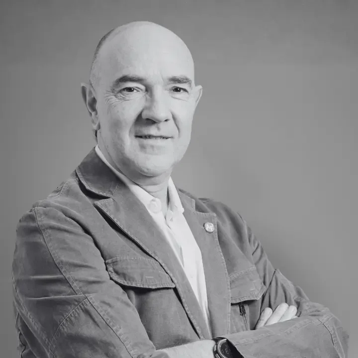 Homme en veste décontractée, bras croisés, souriant, portrait en noir et blanc.