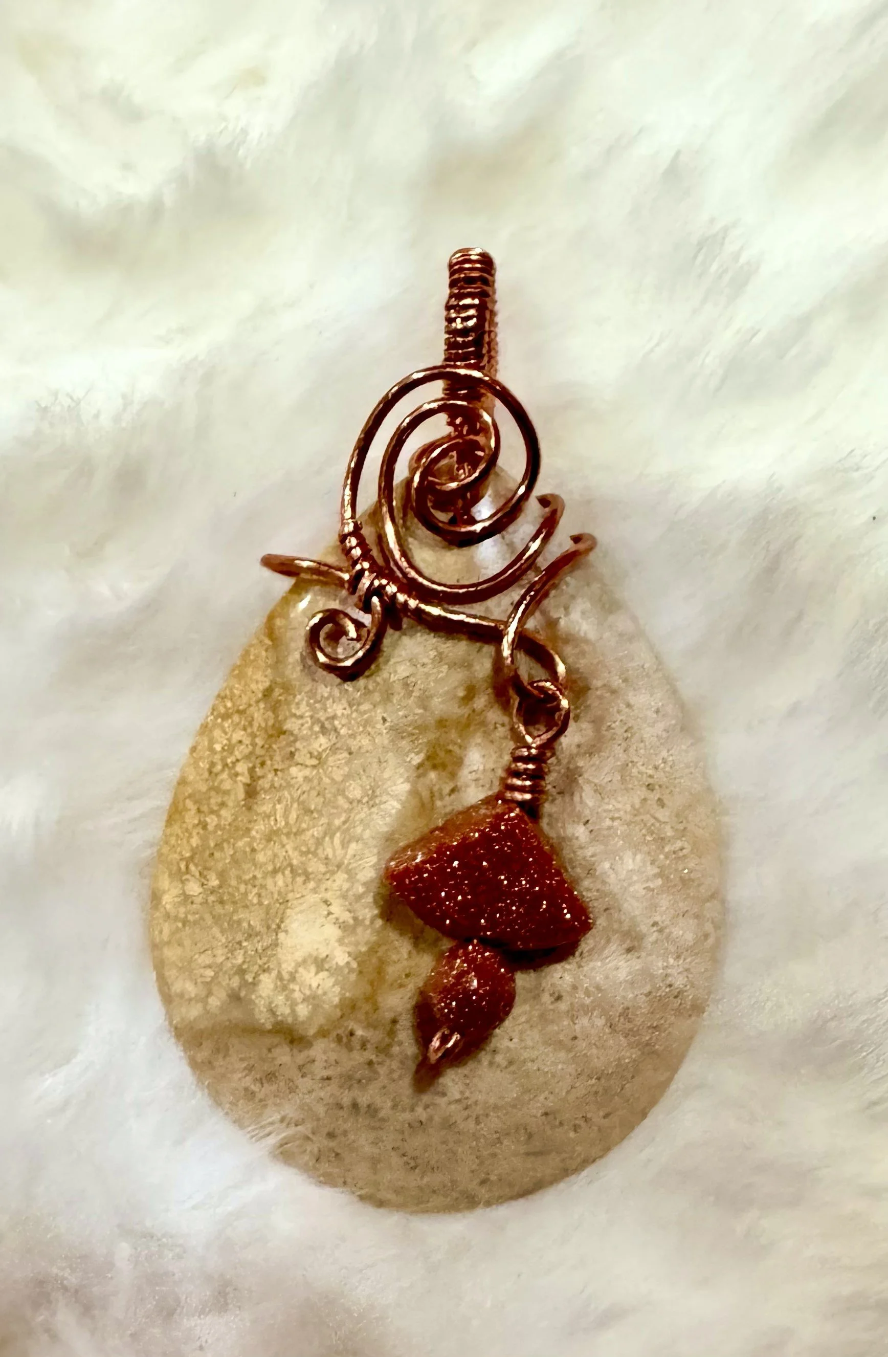 Fossilized corral wrapped in copper with goldstone accents