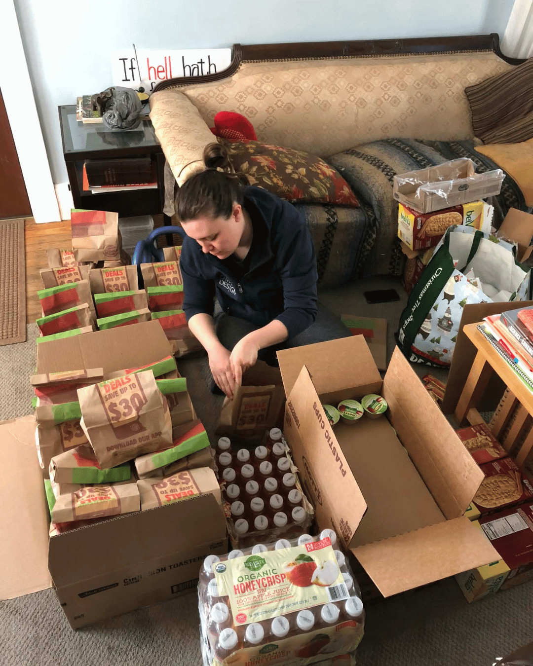 Senate candidate Andrea LaFlamme is show sitting on a floor as she places food items into boxes for a mutual aid food drive event.