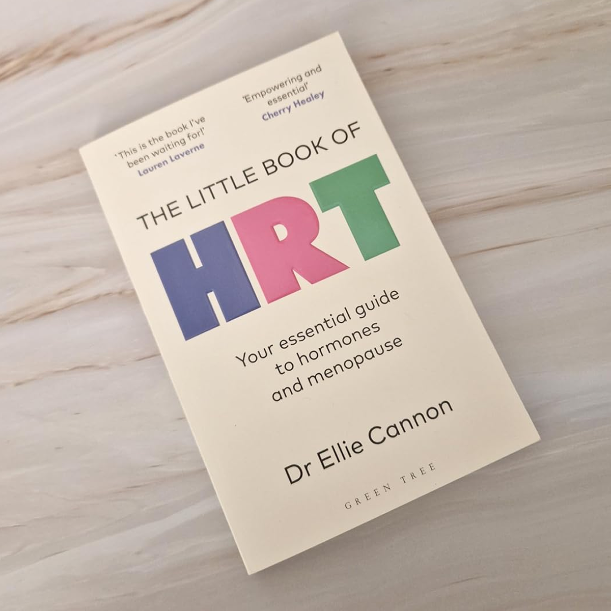 Book titled 'The Little Book of HRT' with subtitle 'Your essential guide to hormones and menopause' by Dr. Ellie Cannon, placed on a light wooden surface.