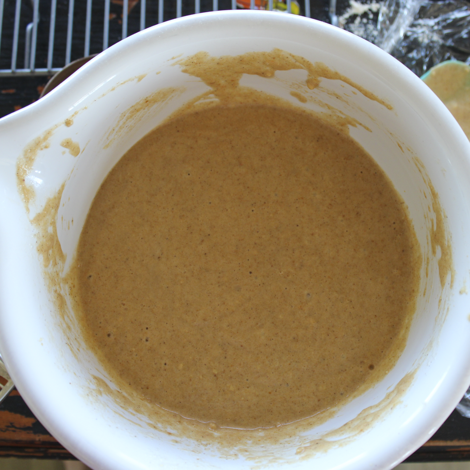 pumpkin waffle batter in a white mixing bowl, sitting on a black chipped table.